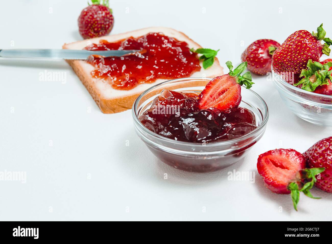 Confiture de fraises maison ou gelée de fraises avec des fraises fraîches mûres sur une assiette blanche. Petit déjeuner avec pain grillé et confiture de fraises. Couteau pour s Banque D'Images