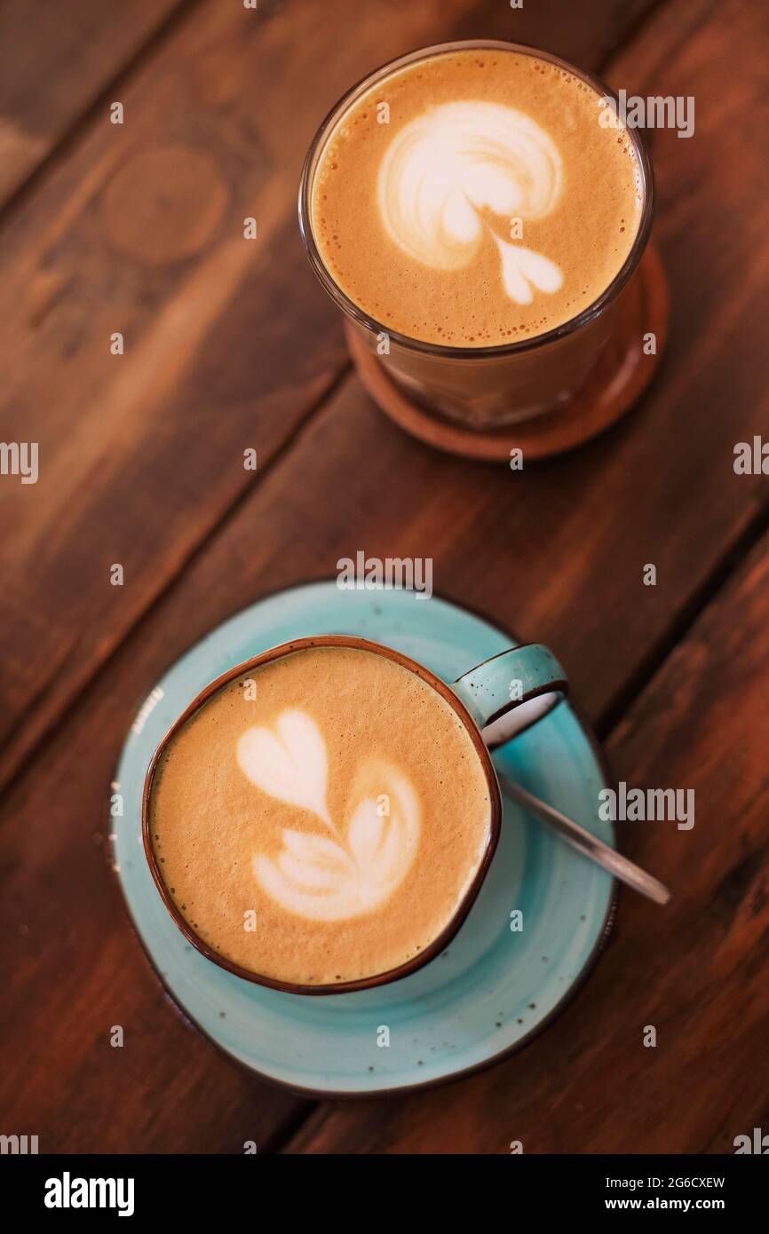 Du dessus des tasses en céramique sur les soucoupes fraîchement brassées latte avec les cœurs sur la mousse Banque D'Images