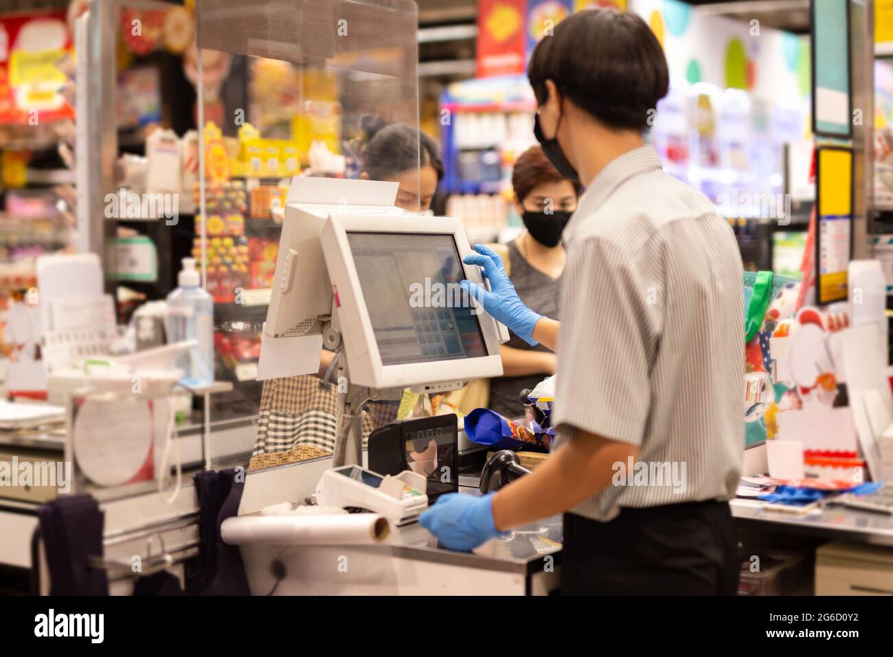 Personnel de caisse masculin avec gant bleu travaillant au comptoir des caisses. Banque D'Images