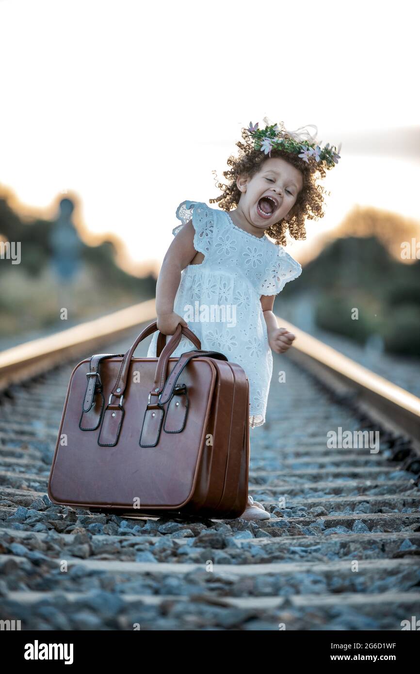 Petite fille ridicule avec sac en cuir debout sur la route de chemin de fer  et montrant le concept de voyage Photo Stock - Alamy