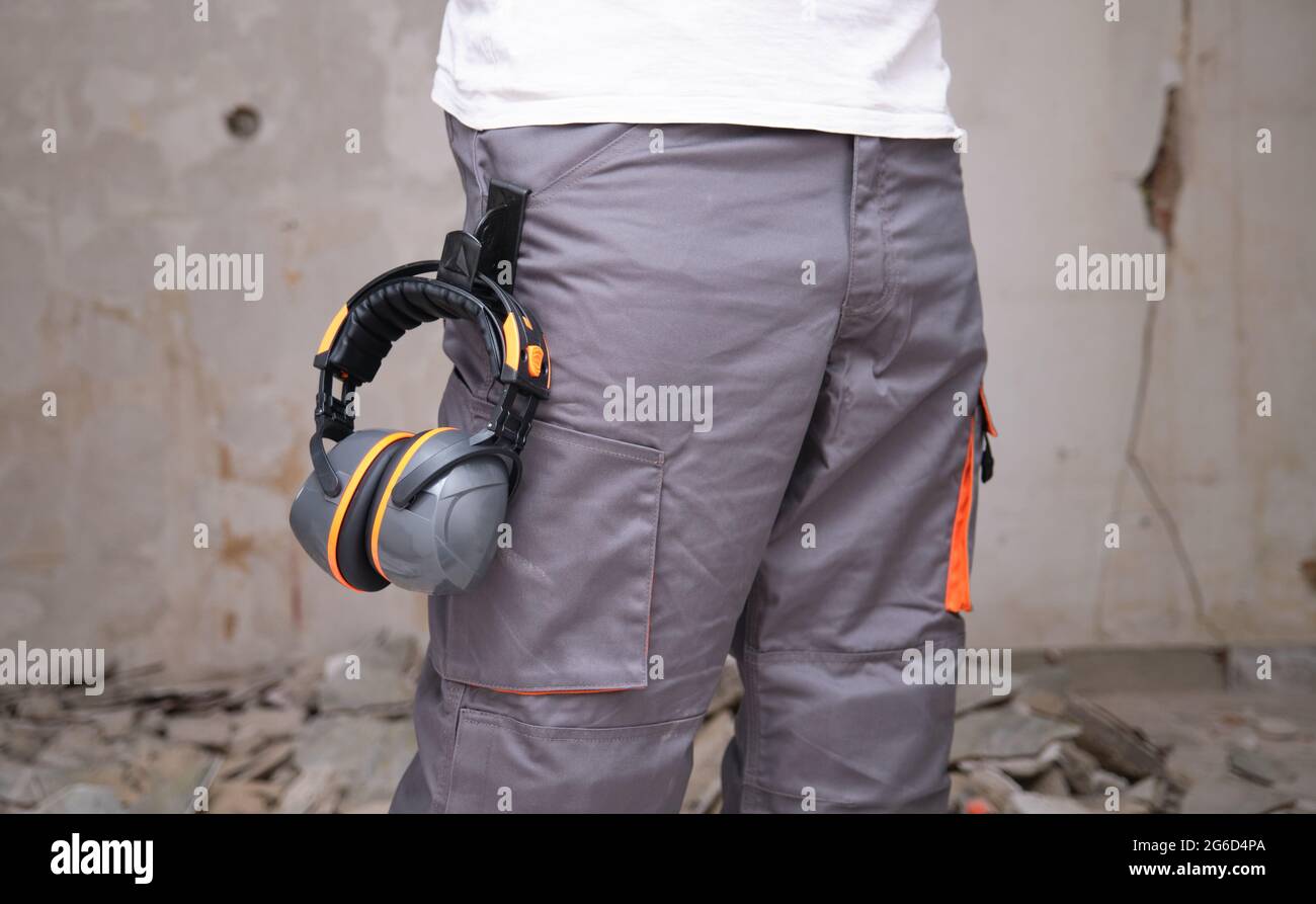 Un fabricant méconnaissable avec une protection auditive accrochée au pantalon. Concept de sécurité au travail. Banque D'Images