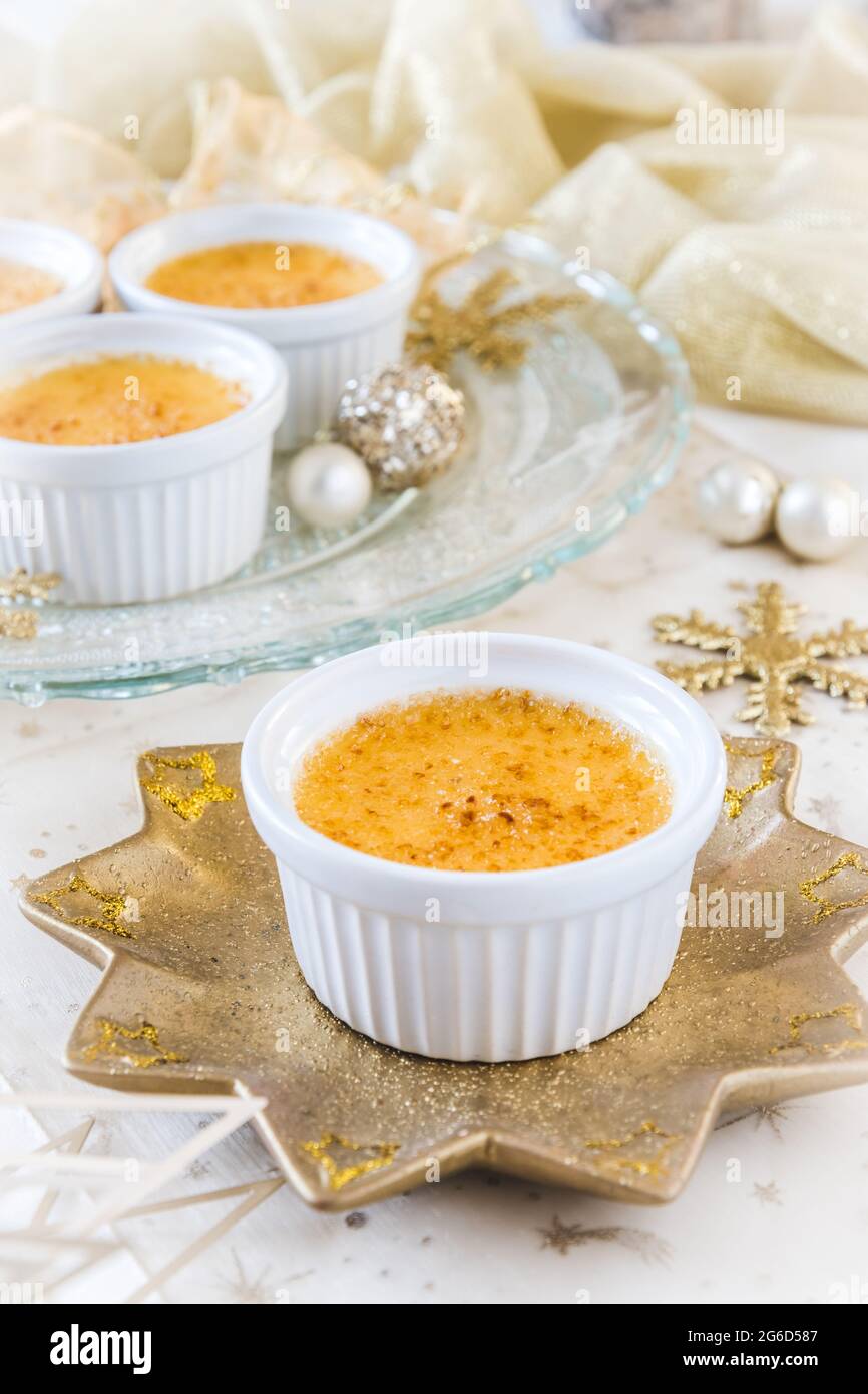 Crème brûlée - dessert traditionnel à la crème vanille française avec du sucre caramélisé sur une assiette en forme d'étoile dorée et un christma doré et blanc Banque D'Images