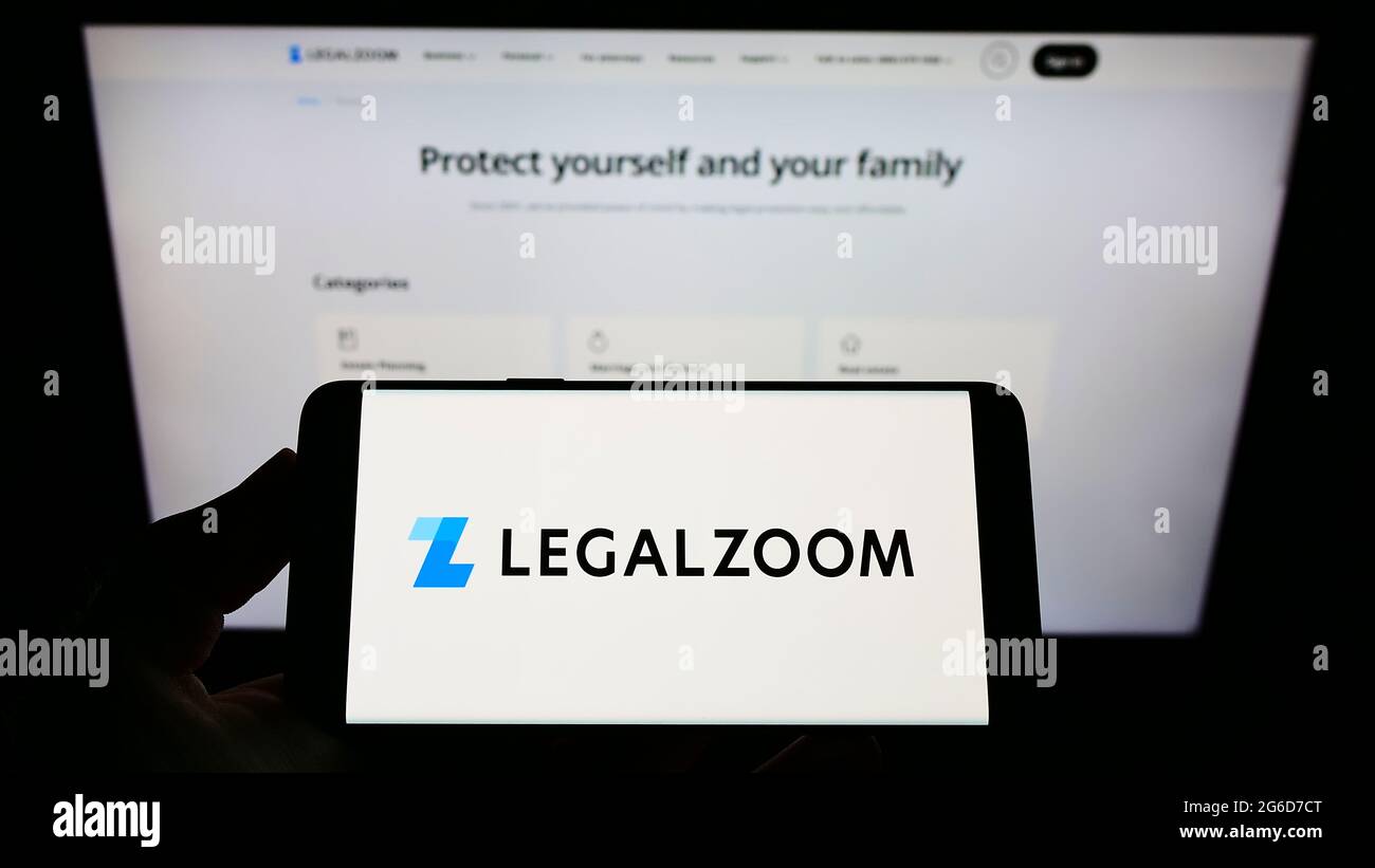 Personne détenant un smartphone portant le logo de la société américaine de technologie juridique LegalZoom.com Inc. À l'écran devant le site Web. Mise au point sur l'affichage du téléphone. Banque D'Images