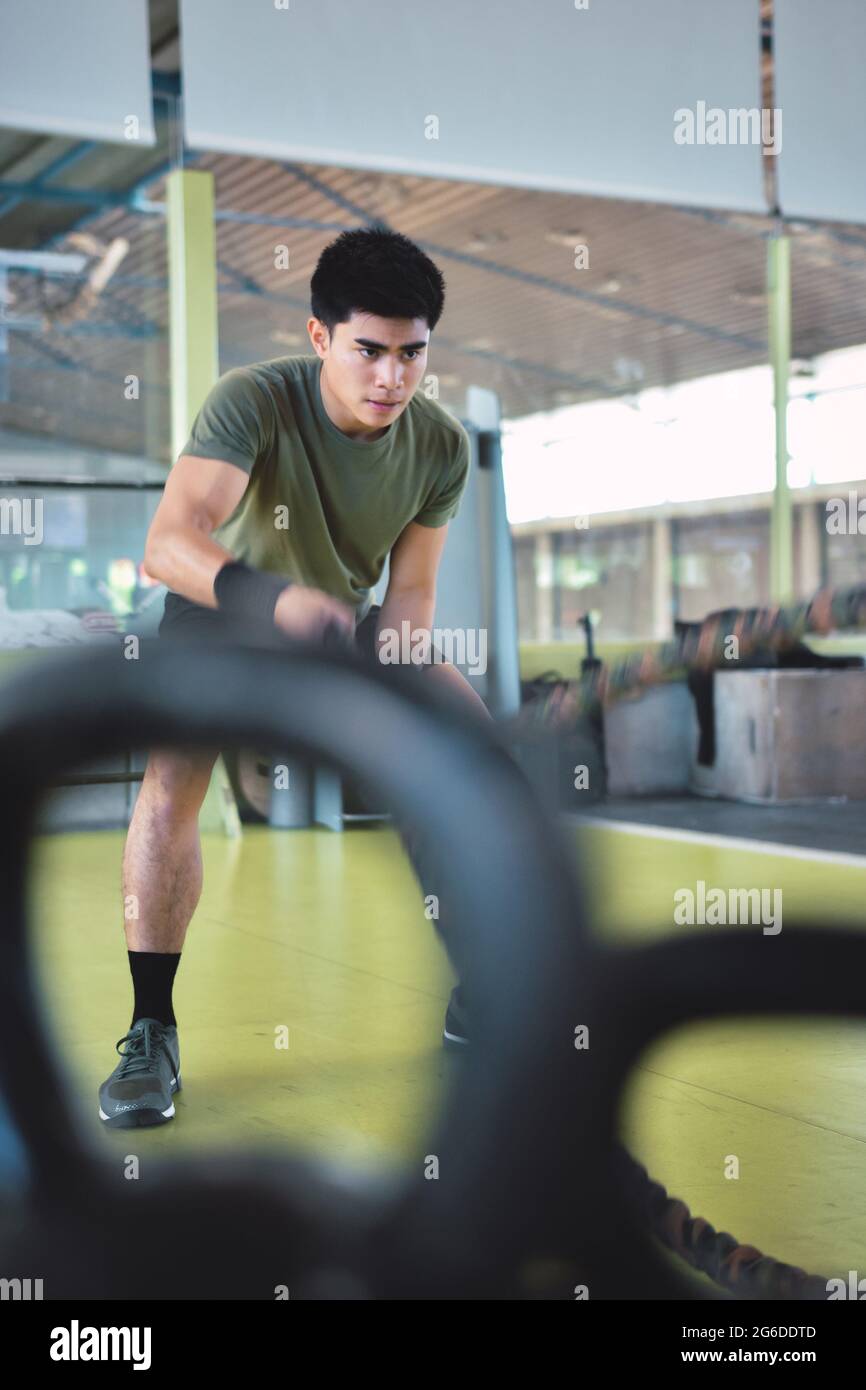 Entraînement d'homme asiatique concentré avec corde de combat dans un gymnase crossfit moderne Banque D'Images