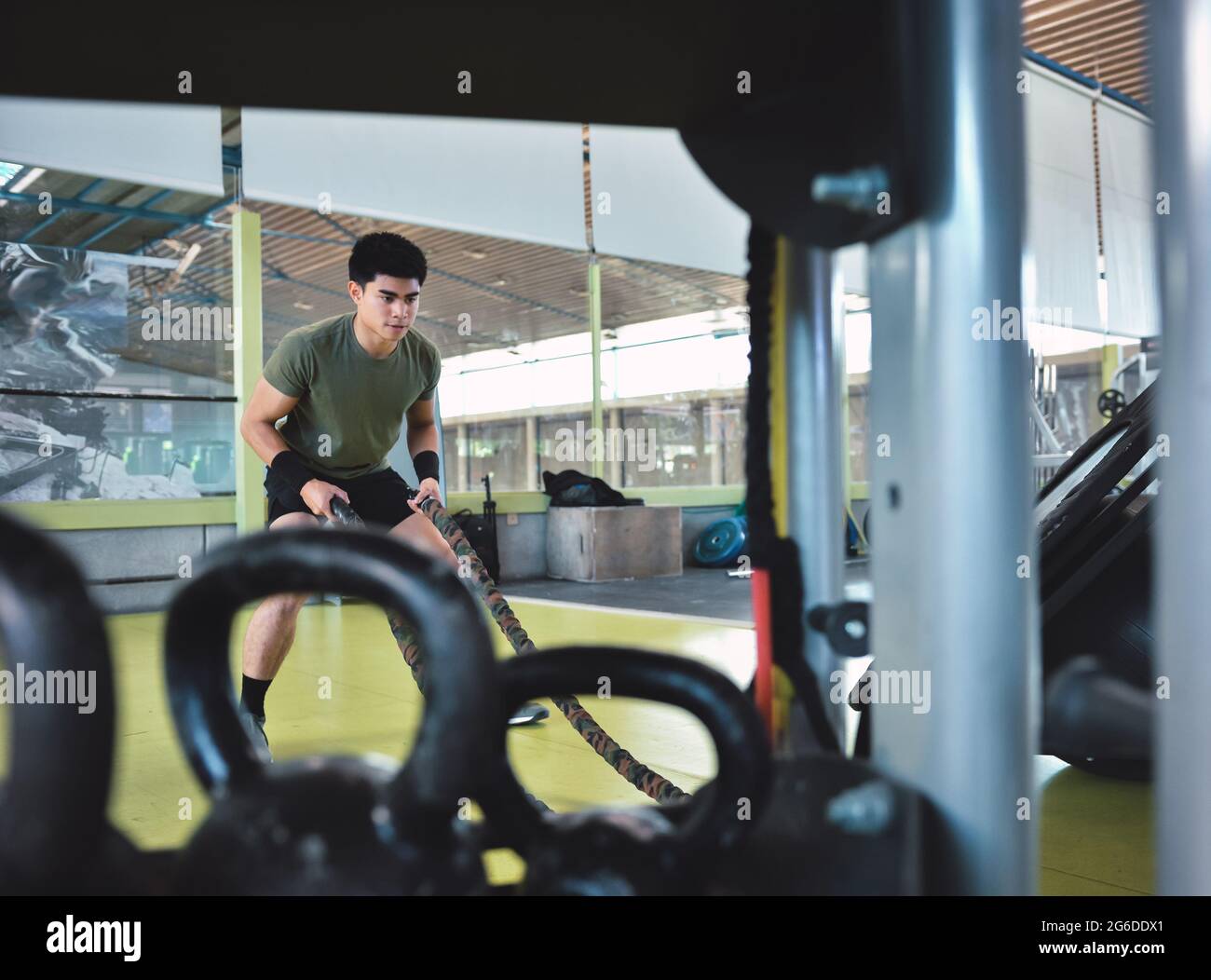 Entraînement d'homme asiatique concentré avec corde de combat dans un gymnase crossfit moderne Banque D'Images