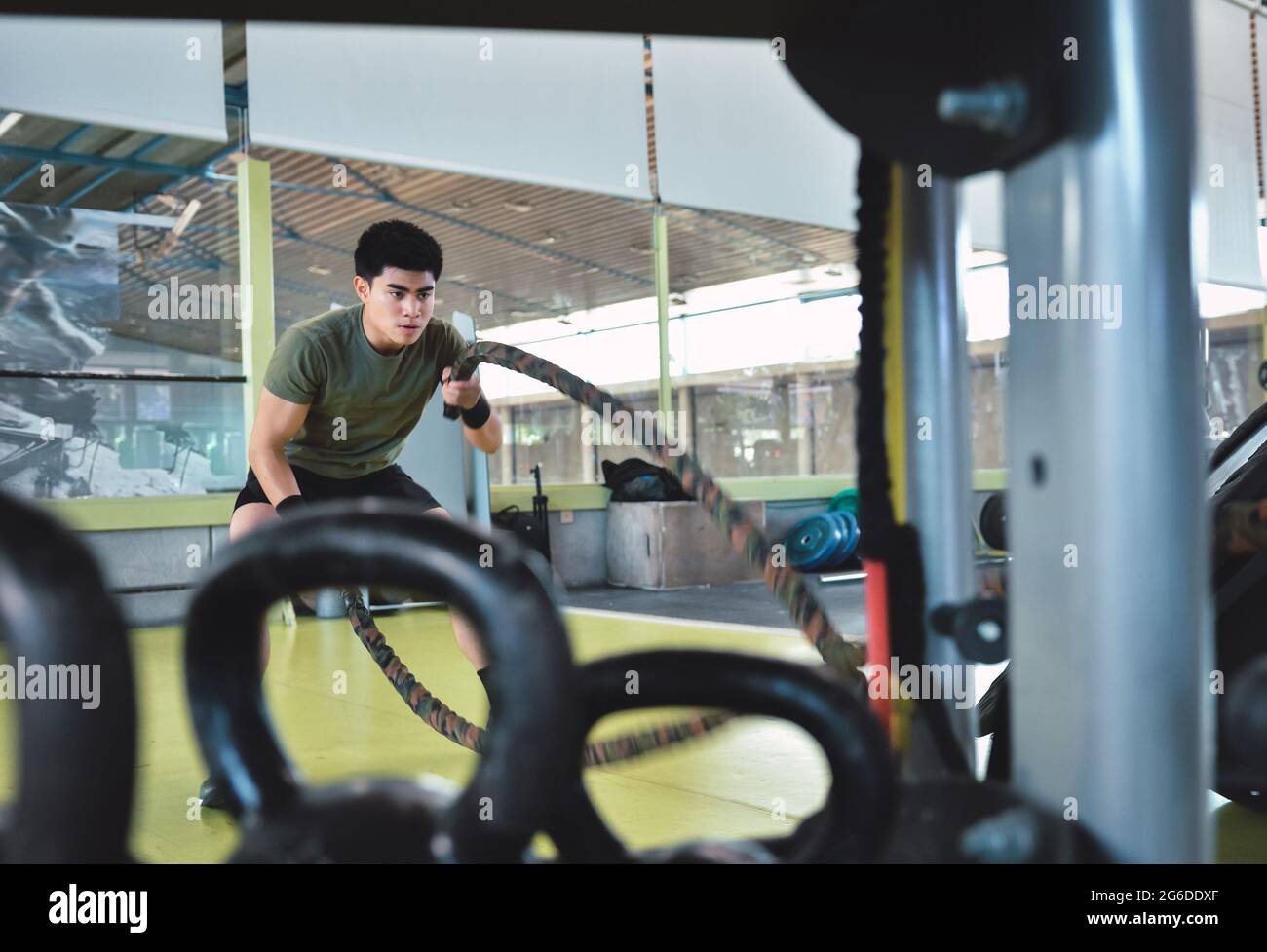 Entraînement d'homme asiatique concentré avec corde de combat dans un gymnase crossfit moderne Banque D'Images