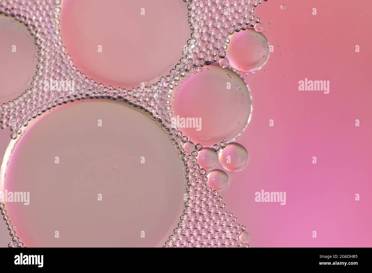 Bulles de couleur rose formées par l'huile dans l'eau. Banque D'Images