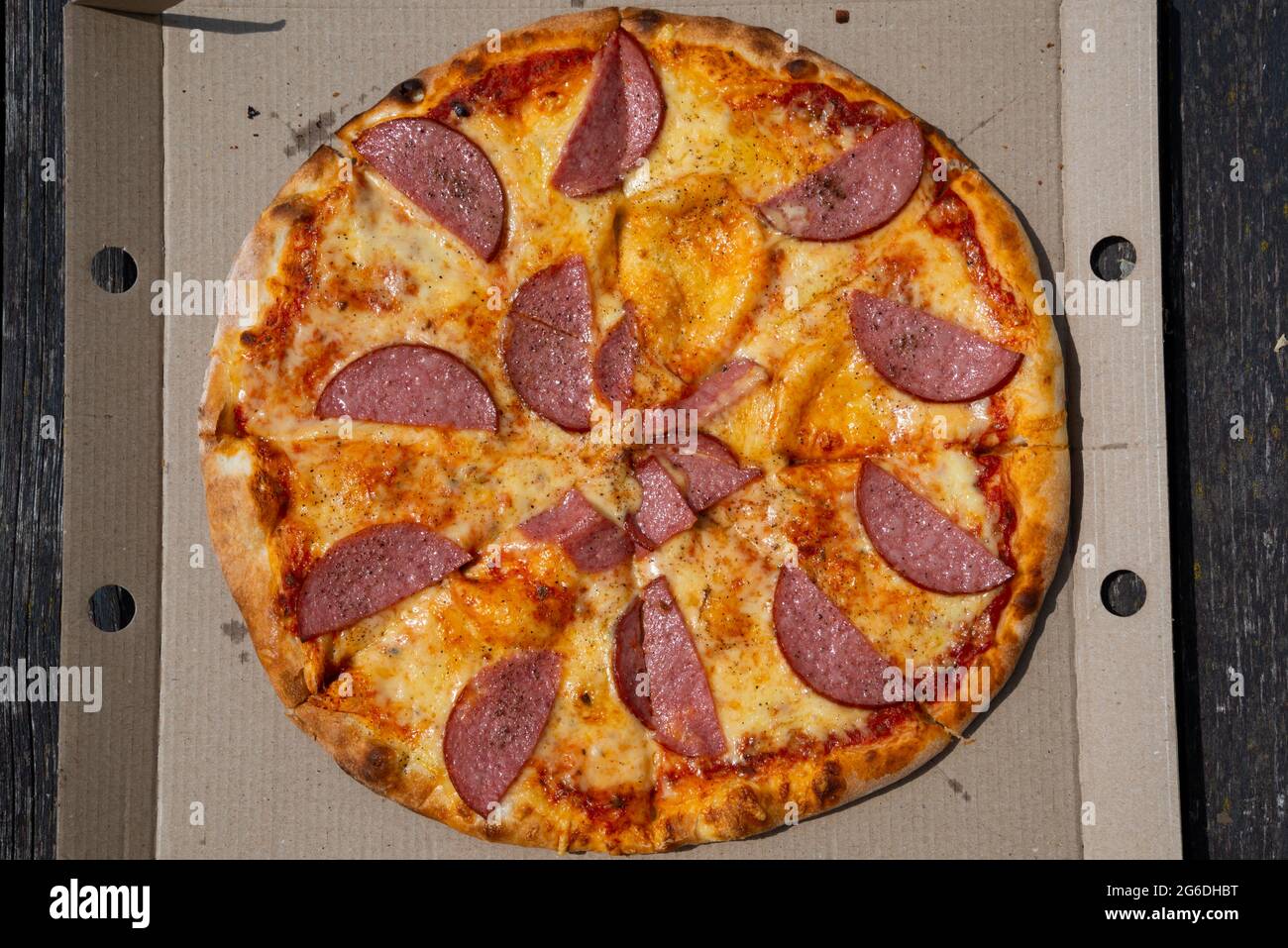 Pizza dans une boîte en carton sur fond sombre. Espace pour le texte. Vue de dessus. Livraison de pizza. Menu pizza. Banque D'Images