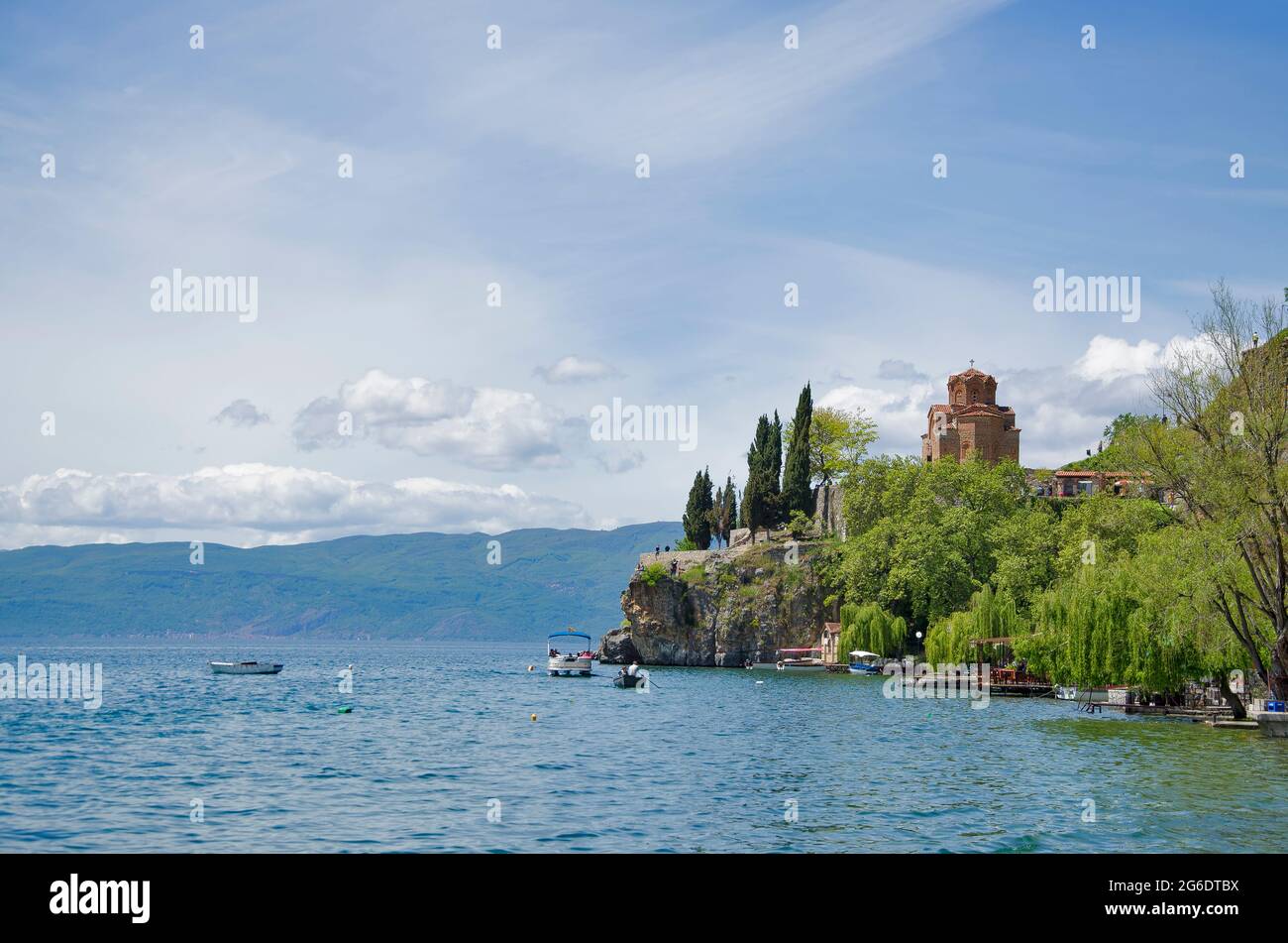 Magnifique vue depuis le lac avec des bateaux, des pierres, une plage, une montagne sur un ciel bleu clair Banque D'Images