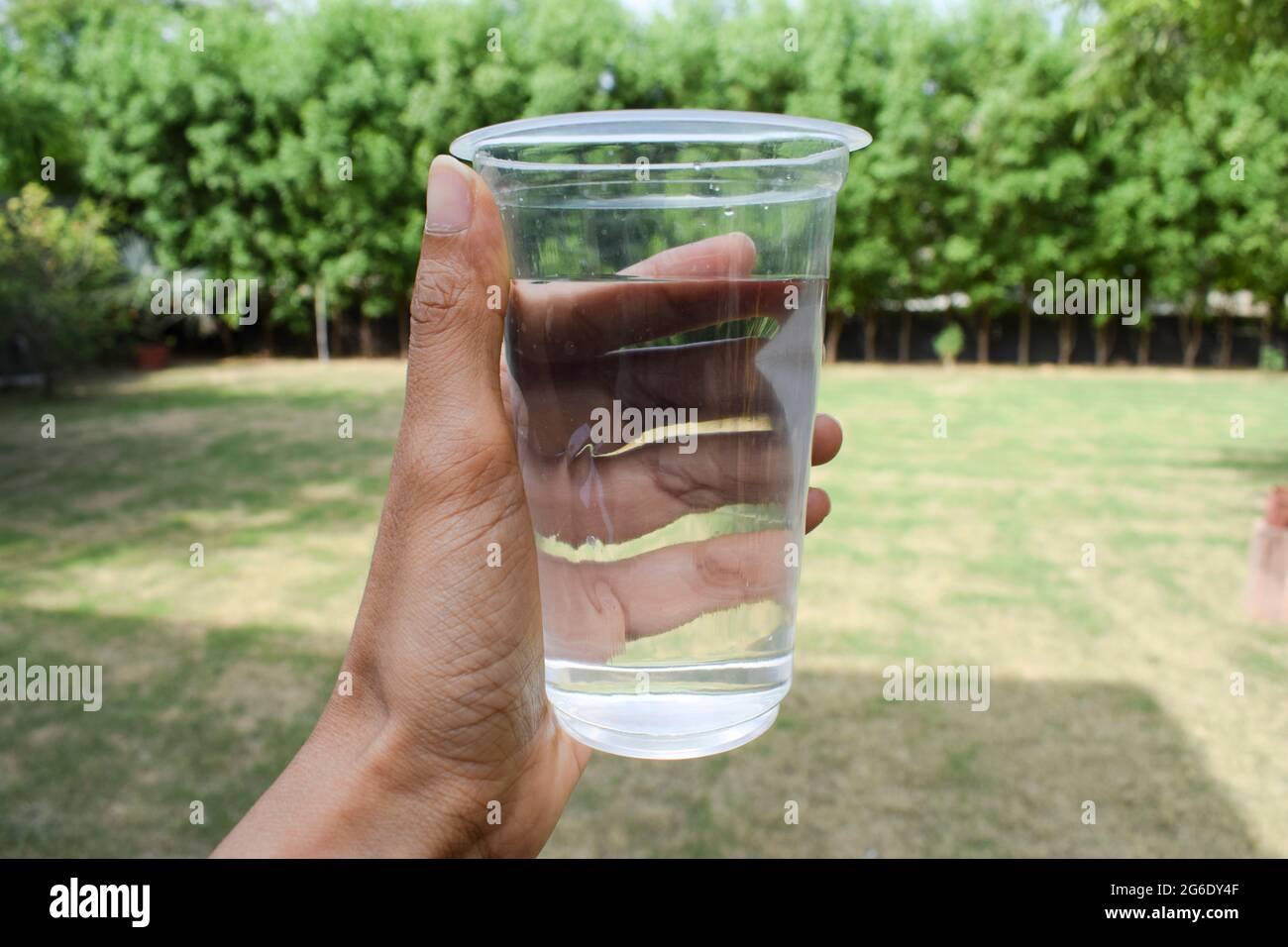 Femme tenant un verre d'eau filtrée propre dans verre jetable transparent  au jardin à la maison avec le fond de la nature environnement ouvert de loi  de verdure Photo Stock - Alamy