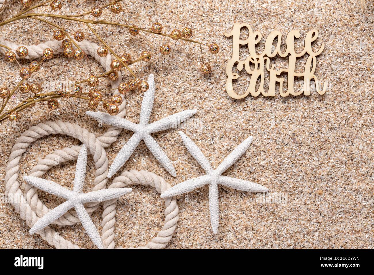 Accueil de vacances sur la plage ou le thème tropical avec boules scintillantes sur brindilles, étoiles de mer blanches, corde nautique, et paix sur Terre sur sable de plage tout dans la nature Banque D'Images