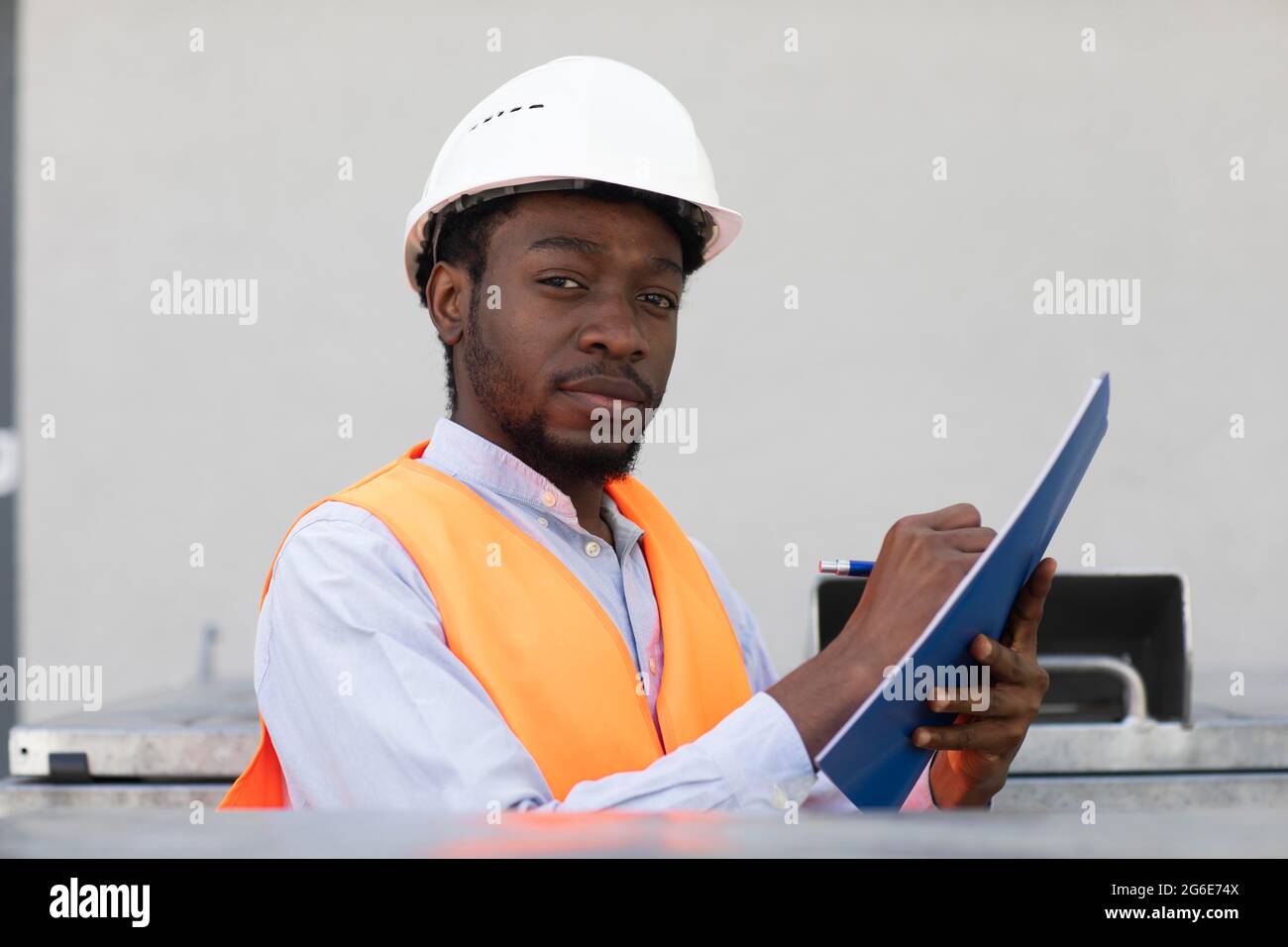 Jeune homme noir travaillant dehors comme technicien avec casque et gilet de sécurité, Fribourg, Bade-Wurtemberg, Allemagne Banque D'Images