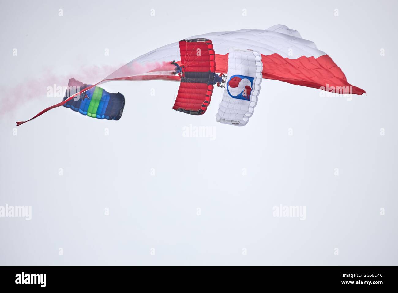 Une démonstration de parachutes en tandem avec le drapeau polonais lors de l'événement Fly Fest 2021 à Piotrków Trybunalski Banque D'Images Une démonstration de parachutes en tandem avec le drapeau polonais lors de l'événement Fly Fest 2021 à Piotrków Trybunalski Banque D'Images