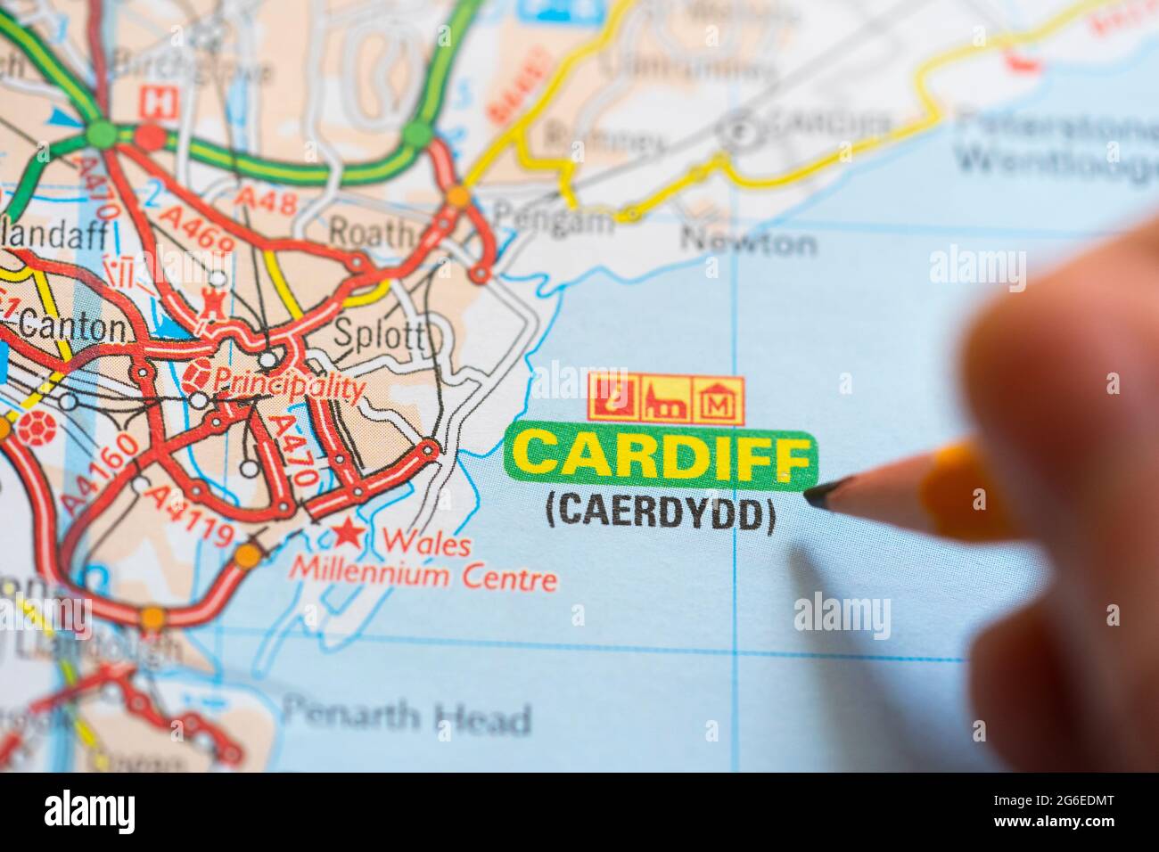 Gros plan d'une page sur une carte routière imprimée atlas avec un homme tenant un crayon pointant vers la capitale du pays de Galles - Cardiff (Caerdydd) Banque D'Images