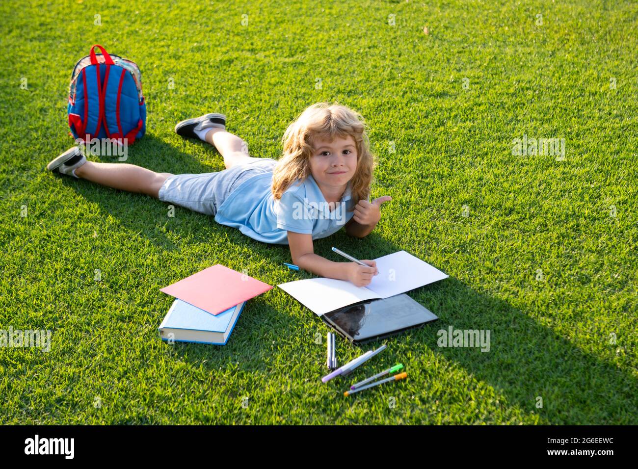 Adorable petit livre de lecture pour enfants à l'extérieur. Un enfant lit le livre dans le parc. Préparation à l'école et à la journée internationale d'alphabétisation. Concept de retour à l'école. Banque D'Images