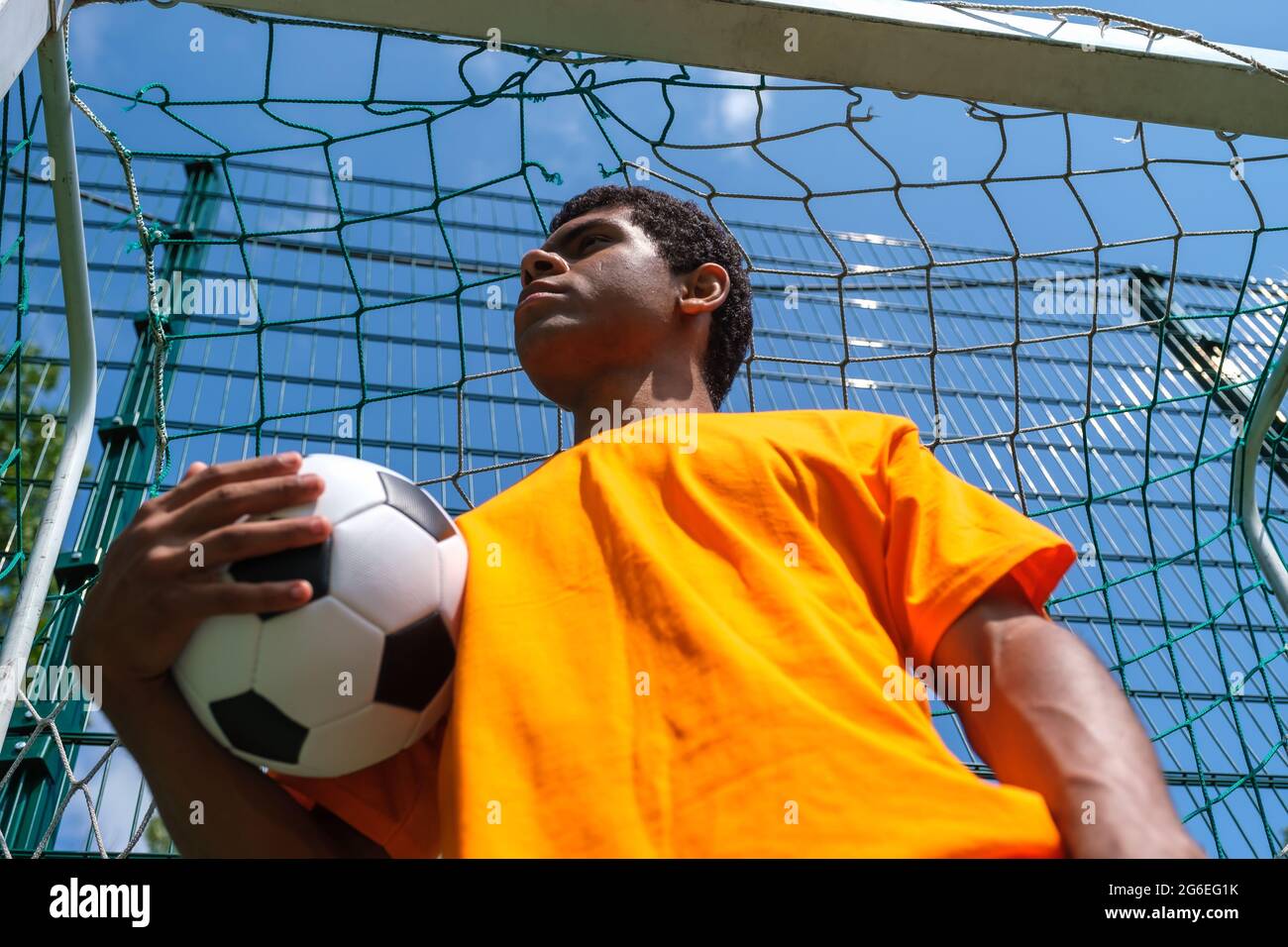 Homme afro-américain tenant le ballon de football tout en se tenant dans le but de football Banque D'Images