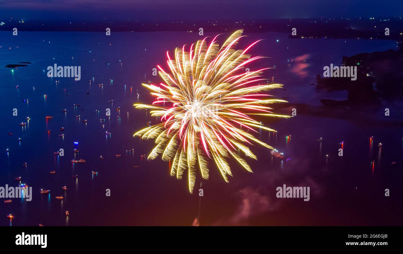 Feu d'artifice le quatrième juillet tiré d'une barge sur un lac pris avec un drone. Banque D'Images