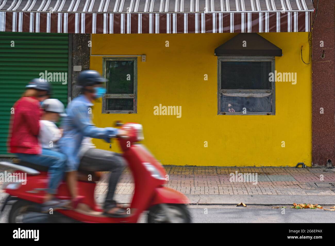 Une famille asiatique floue fait une moto sur le fond d'un mur jaune. Trafic de rue Vietnam. Nha Trang, Vietnam Banque D'Images