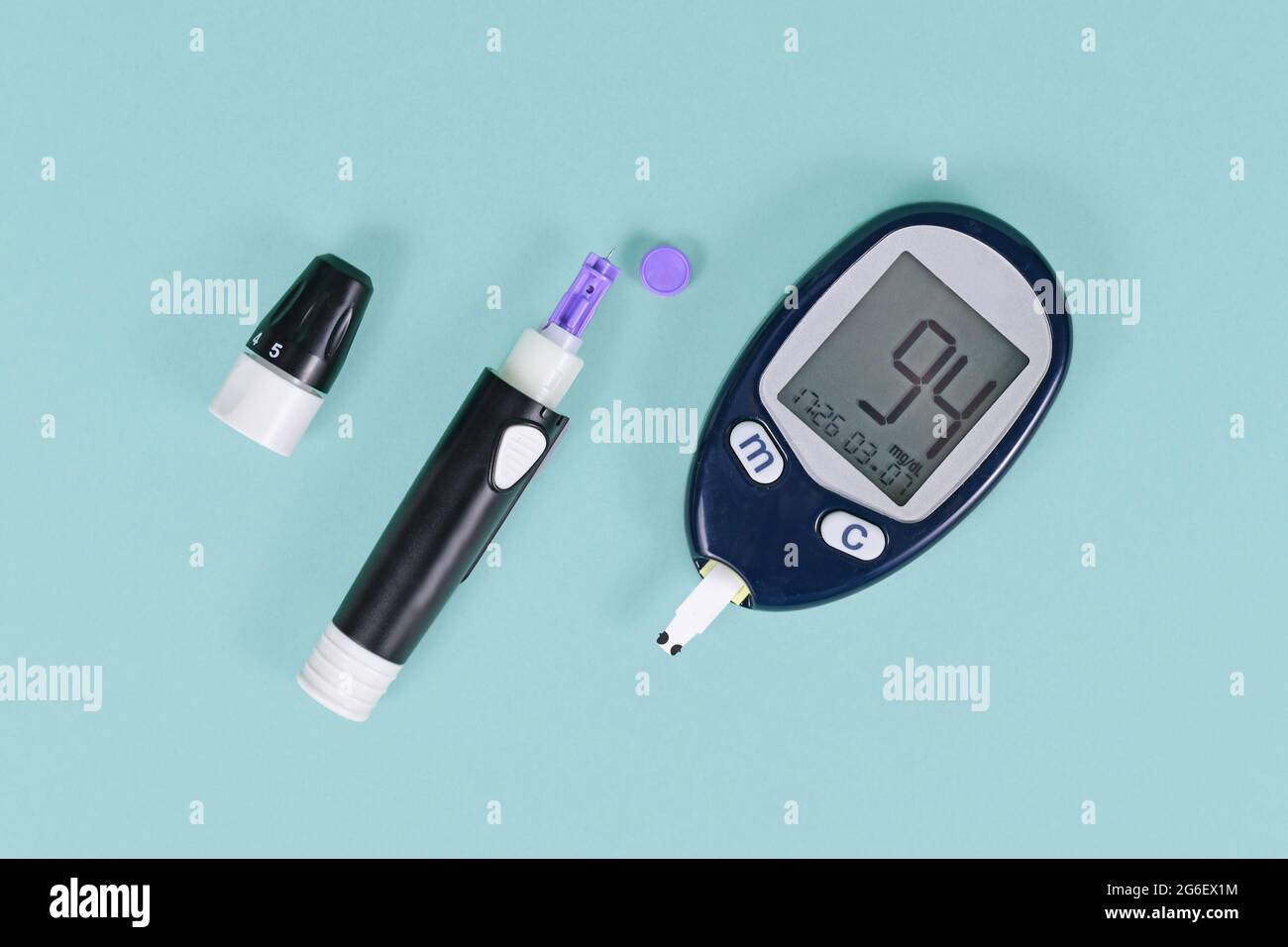 Outils pour le traitement du diabète avec glucomètre de sang montrant le sucre de sang de 94 et dispositif de lancette avec lancette sur fond bleu Banque D'Images