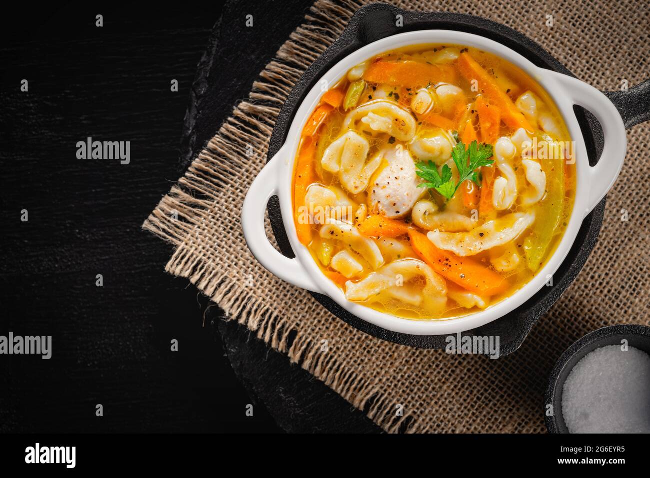 Soupe de poulet maison russe avec nouilles et légumes dans une assiette blanche sur fond noir Banque D'Images