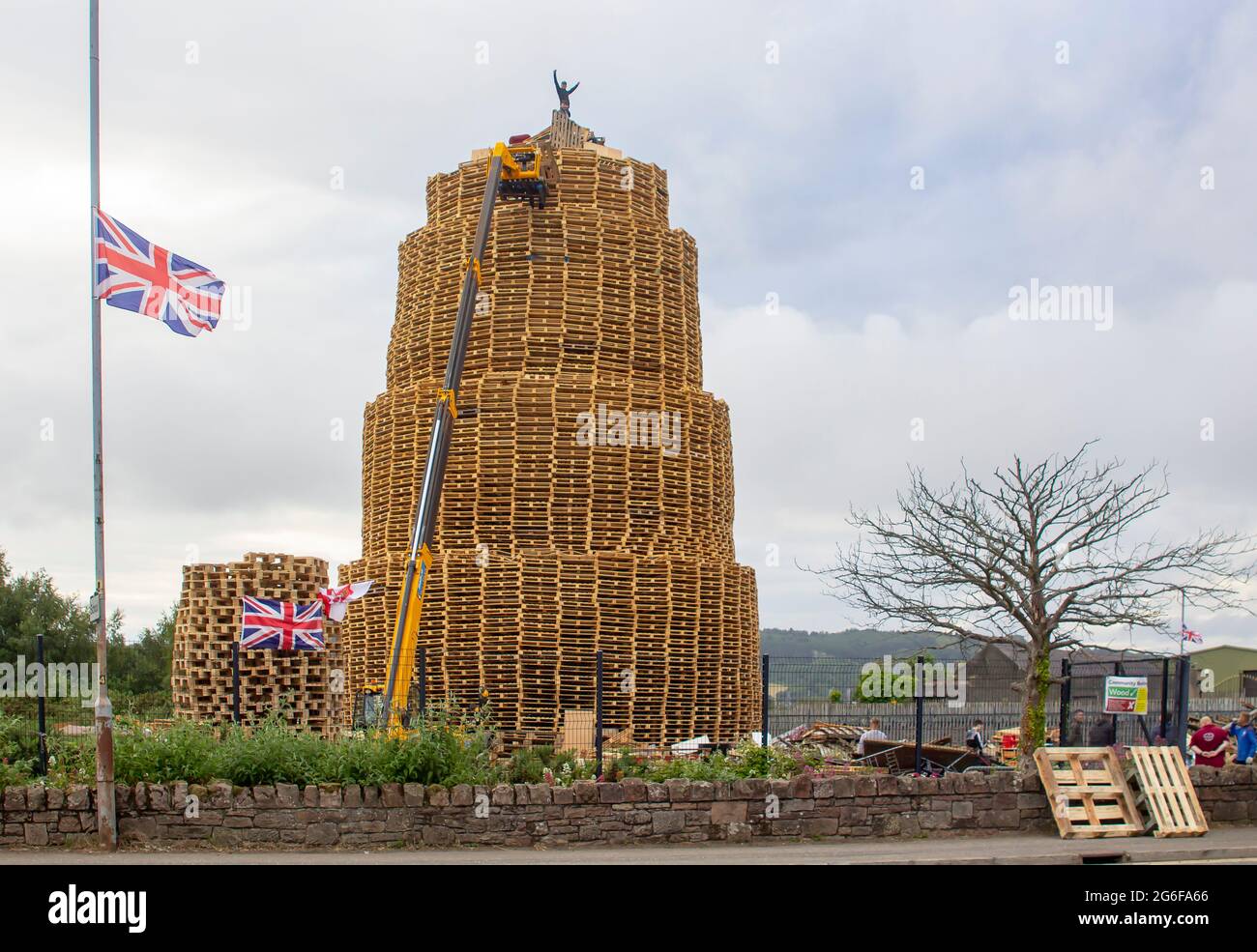 4 juillet 2021 jeunes sur le très grand feu de joie fait de milliers de palettes industrielles en bois comme ils se préparent pour les célébrations du 12 juillet Banque D'Images