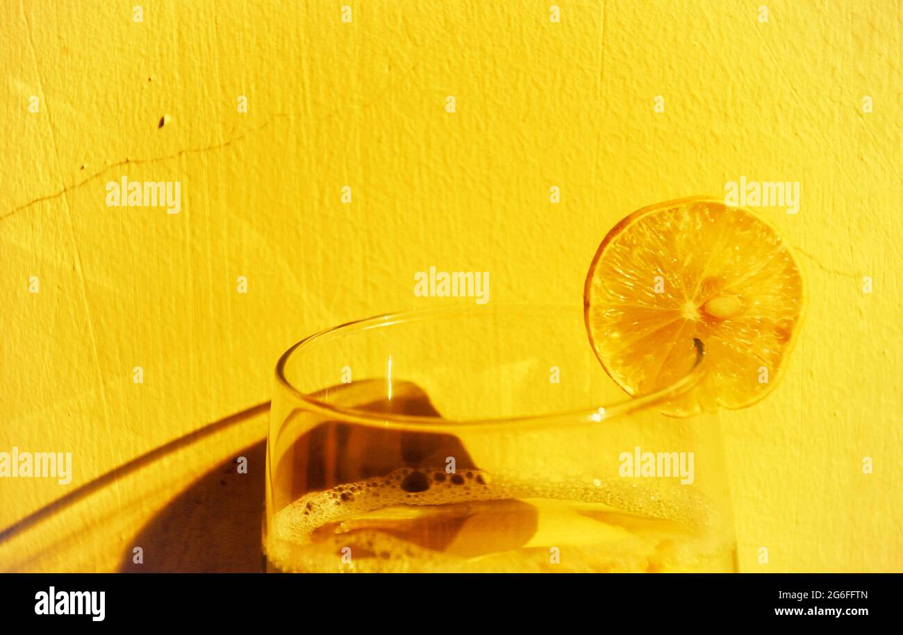 Gros plan d'un cocktail avec du citron sur fond jaune Banque D'Images