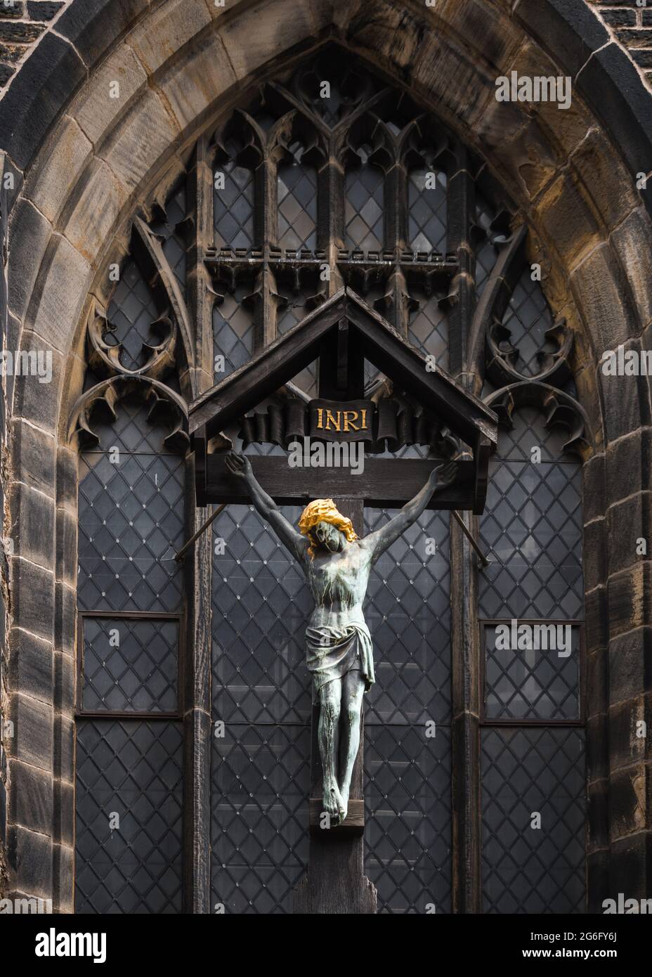 Statue de Jésus sur le crucifix accrochée devant la vieille église abandonnée et abandonnée. Couleur or devant la fenêtre en vitrail. Banque D'Images