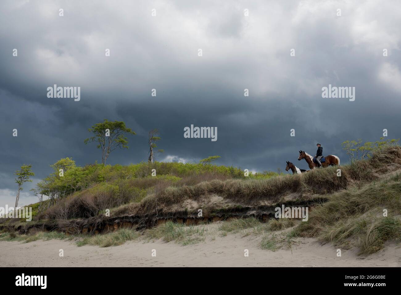 Fille à cheval dans l'herbe de plage sous ciel orageux Banque D'Images