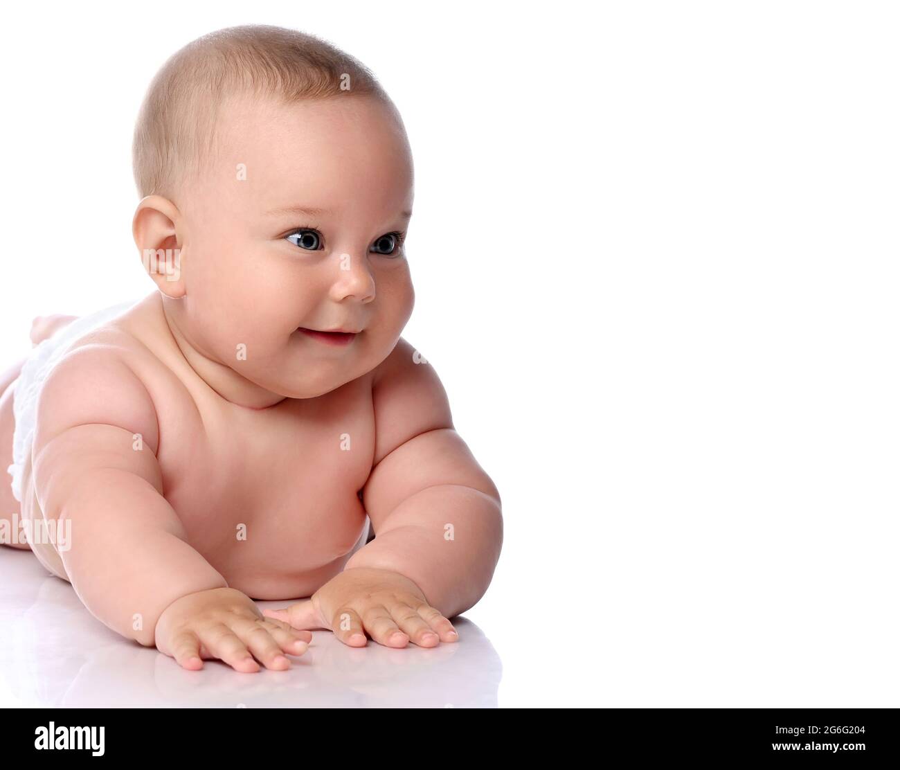 Portrait d'un bébé heureux enfant bébé fille enfant dans un couches allongé sur son ventre, estomac regardant de côté à l'espace de copie Banque D'Images