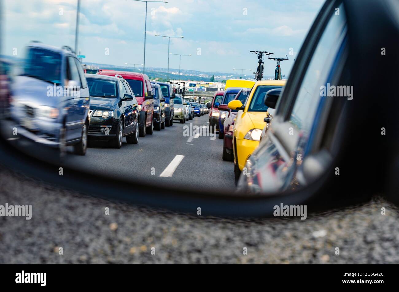 Embouteillage sur l'autoroute européenne avec une grande ville en arrière-plan - beaucoup de voitures dans la file d'attente vu depuis le rétroviseur intérieur Banque D'Images