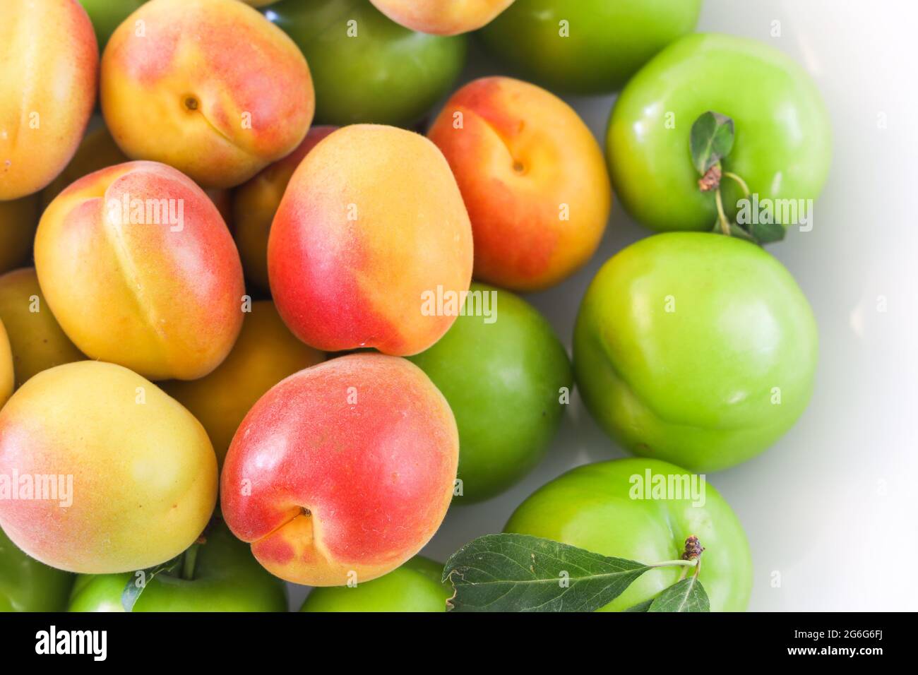 Groupe de prunes jaunes, rouges et vertes, abricot sur fond blanc, concept alimentaire, espace copie, vue de dessus. Banque D'Images