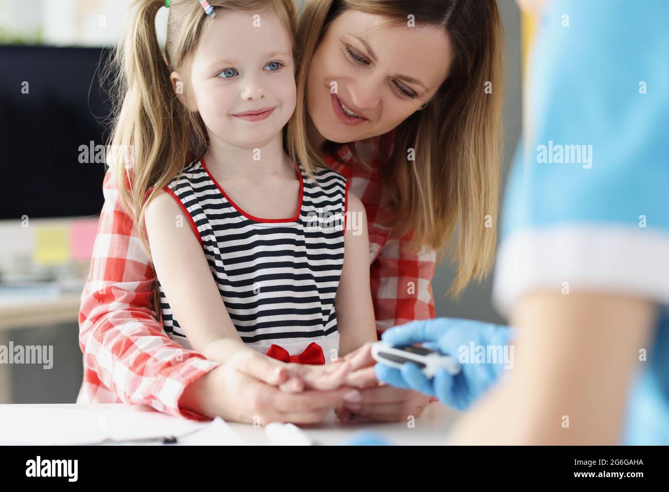 Le médecin vérifie le taux de sucre dans le sang de la petite fille à l'aide d'un glucomètre numérique à l'hôpital Banque D'Images