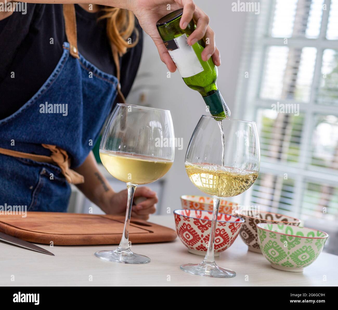 Femme versant du vin dans des verres dans la cuisine Banque D'Images