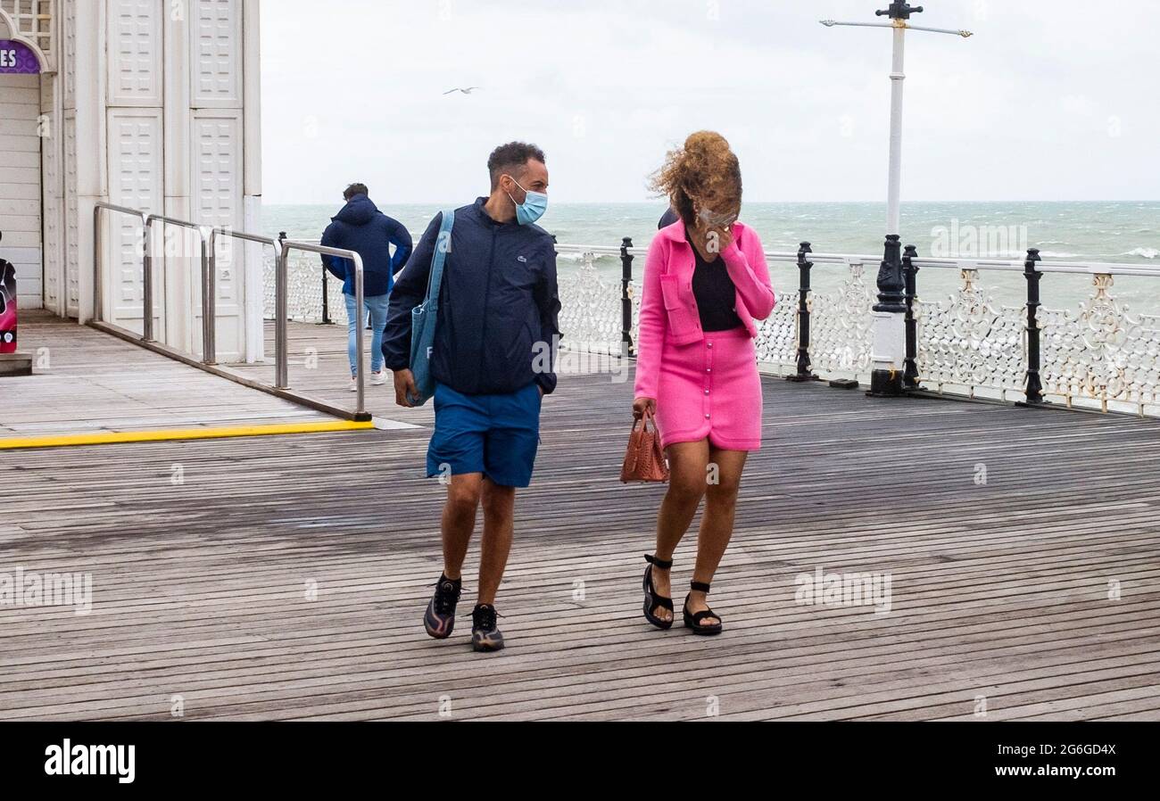 Brighton Royaume-Uni 6 juillet 2021 - les visiteurs se battent contre les vents forts sur la jetée de Brighton avec des rafales de prévisions de jusqu'à 40 miles par heure pour certaines régions : crédit Simon Dack / Alamy Live News Banque D'Images