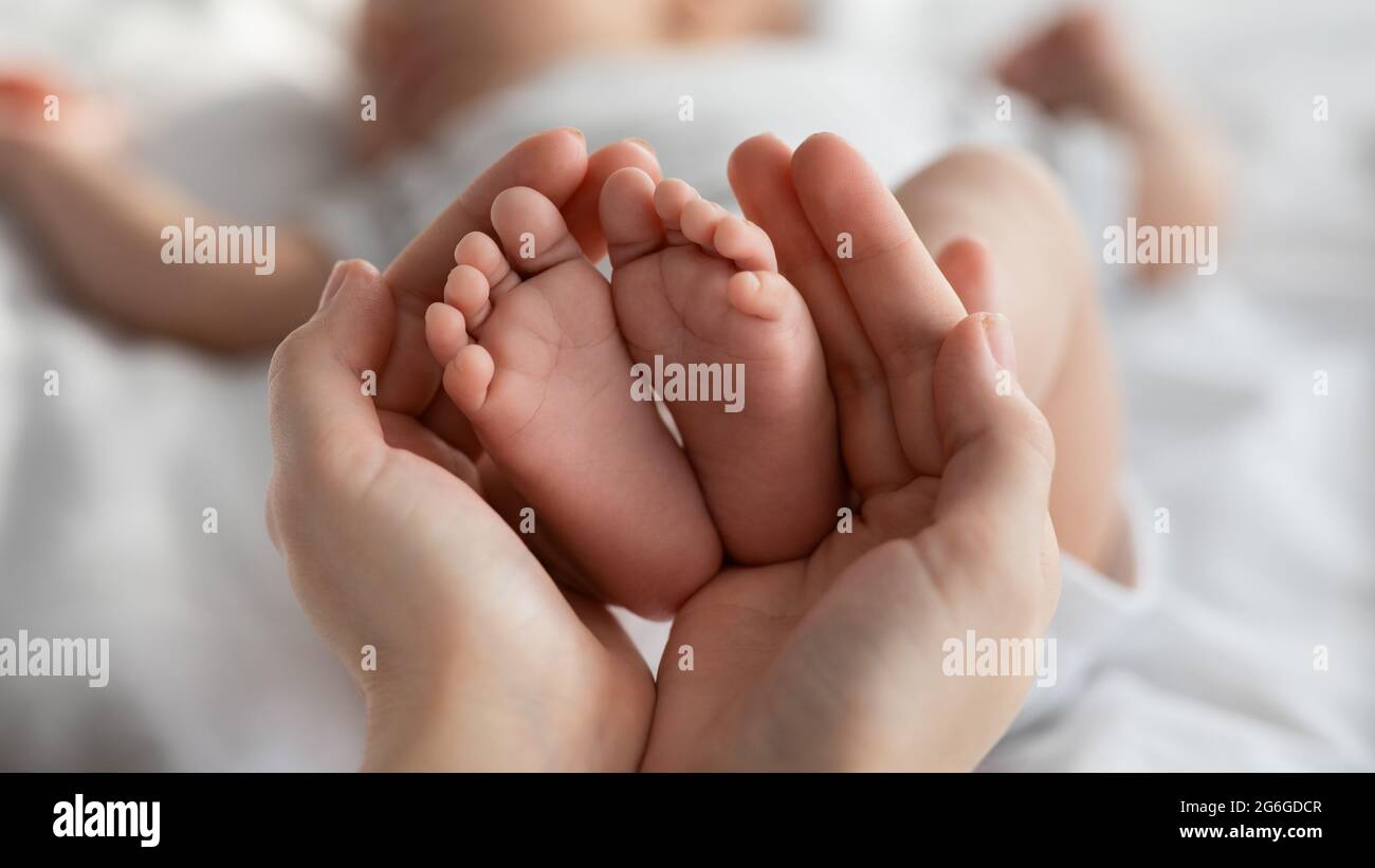 Gros plan des petits pieds de nouveau-né dans les mains de la mère Banque D'Images