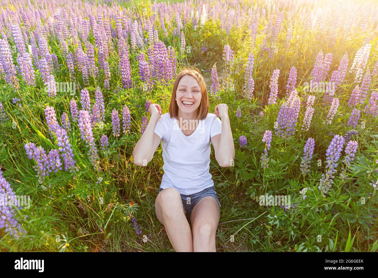 Bonne fille souriante à l'extérieur. Belle jeune femme brunete se reposant sur le terrain d'été avec fleurs sauvages fleur de fond vert. Gratuit Happy european Banque D'Images