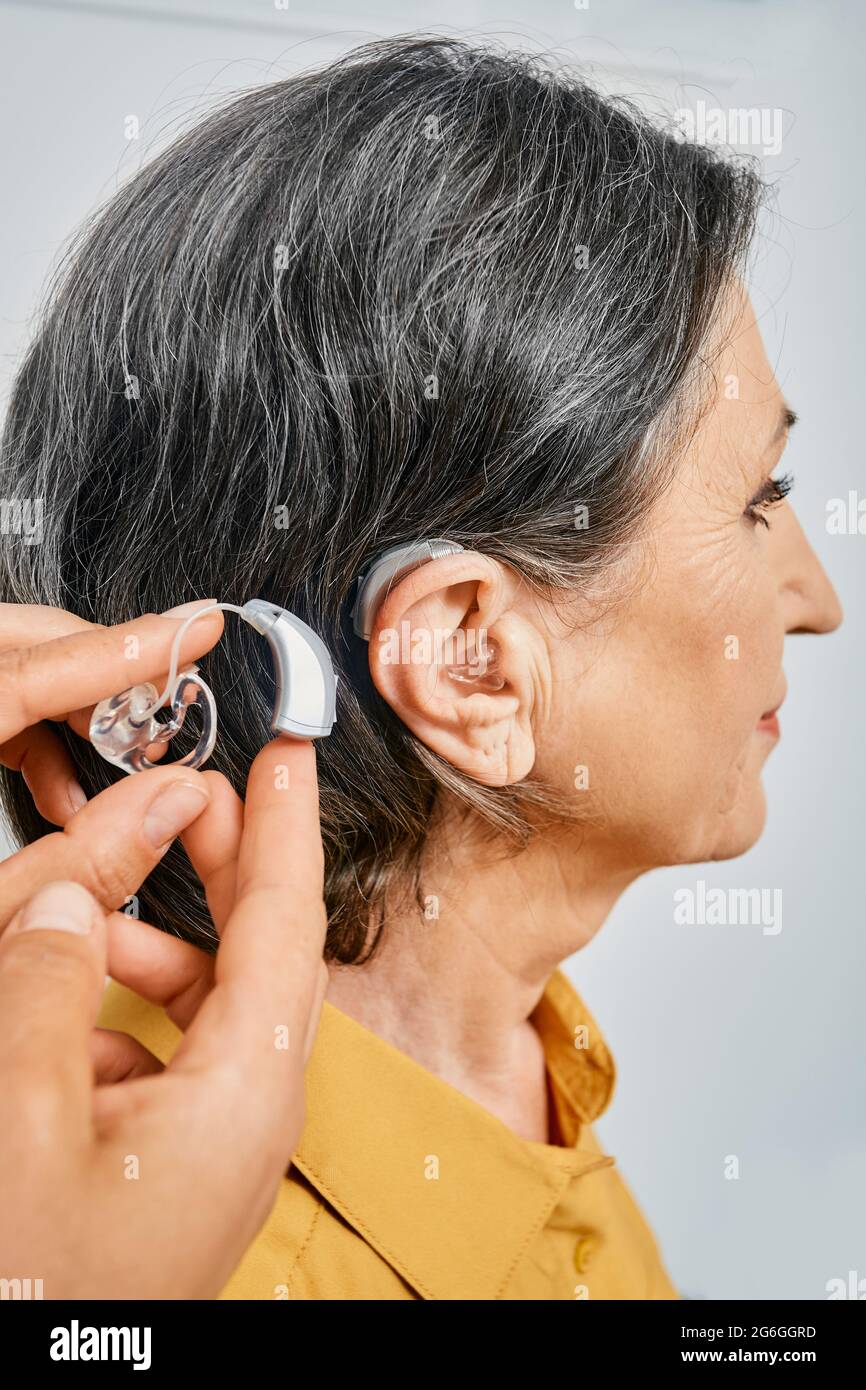 Gros plan de l'aide auditive près de l'oreille du patient adulte. Solutions auditives Banque D'Images