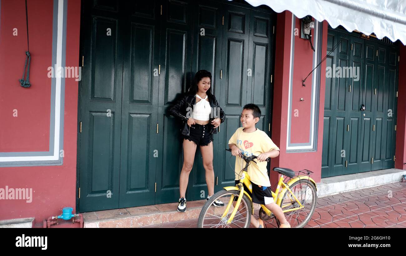 Chinoise asiatique Femme modèle Poser actrice portant Black Leather Jacket blanc Chemisier debout dans la porte en bois d'une maison du patrimoine Bangkok Thaïlande Banque D'Images