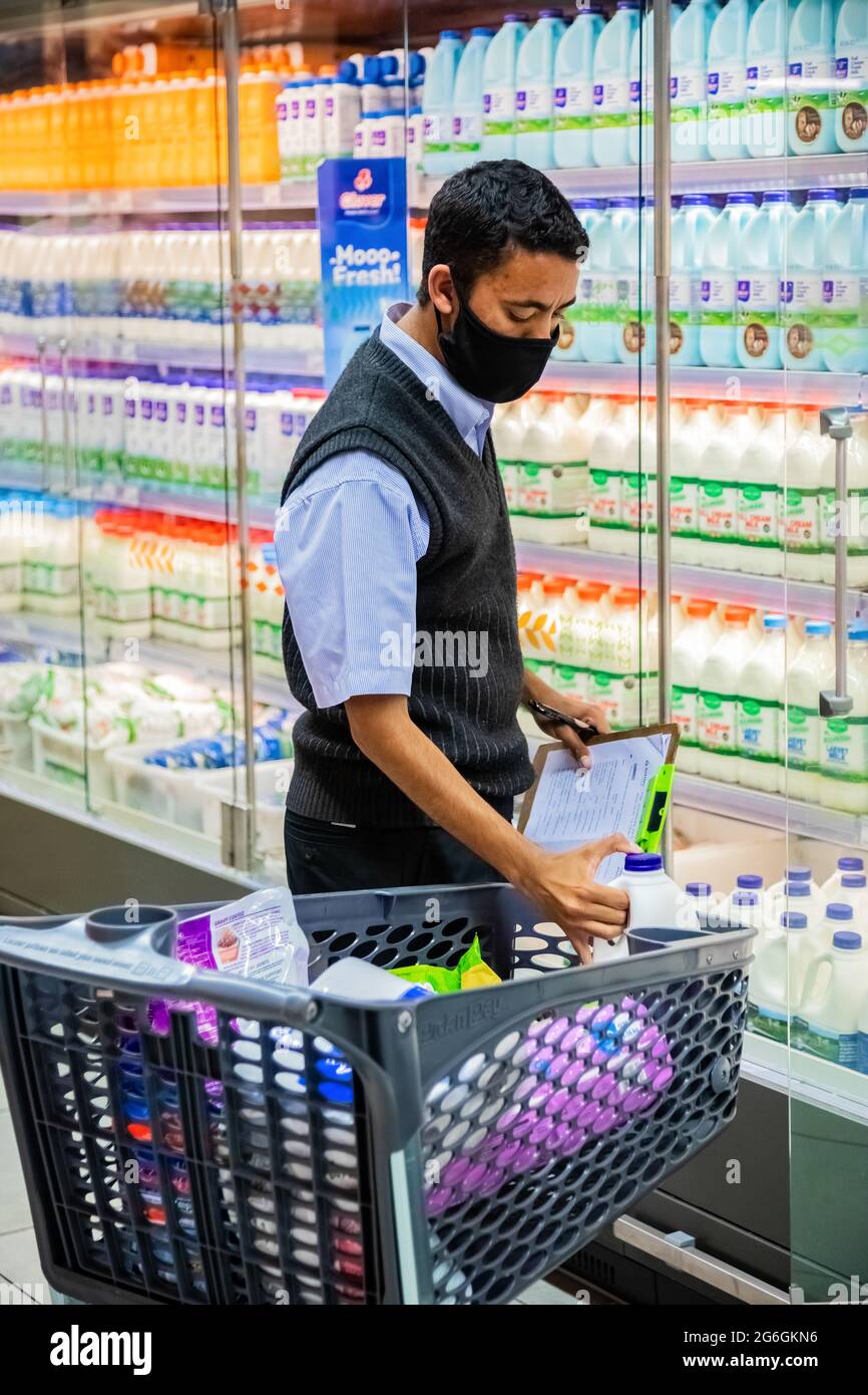 Cape Town, Afrique du Sud - 10 décembre 2020 : membre du personnel qui cueille les produits d'épicerie de l'étagère pour un service de livraison express à domicile au service local Pick n Pay su Banque D'Images