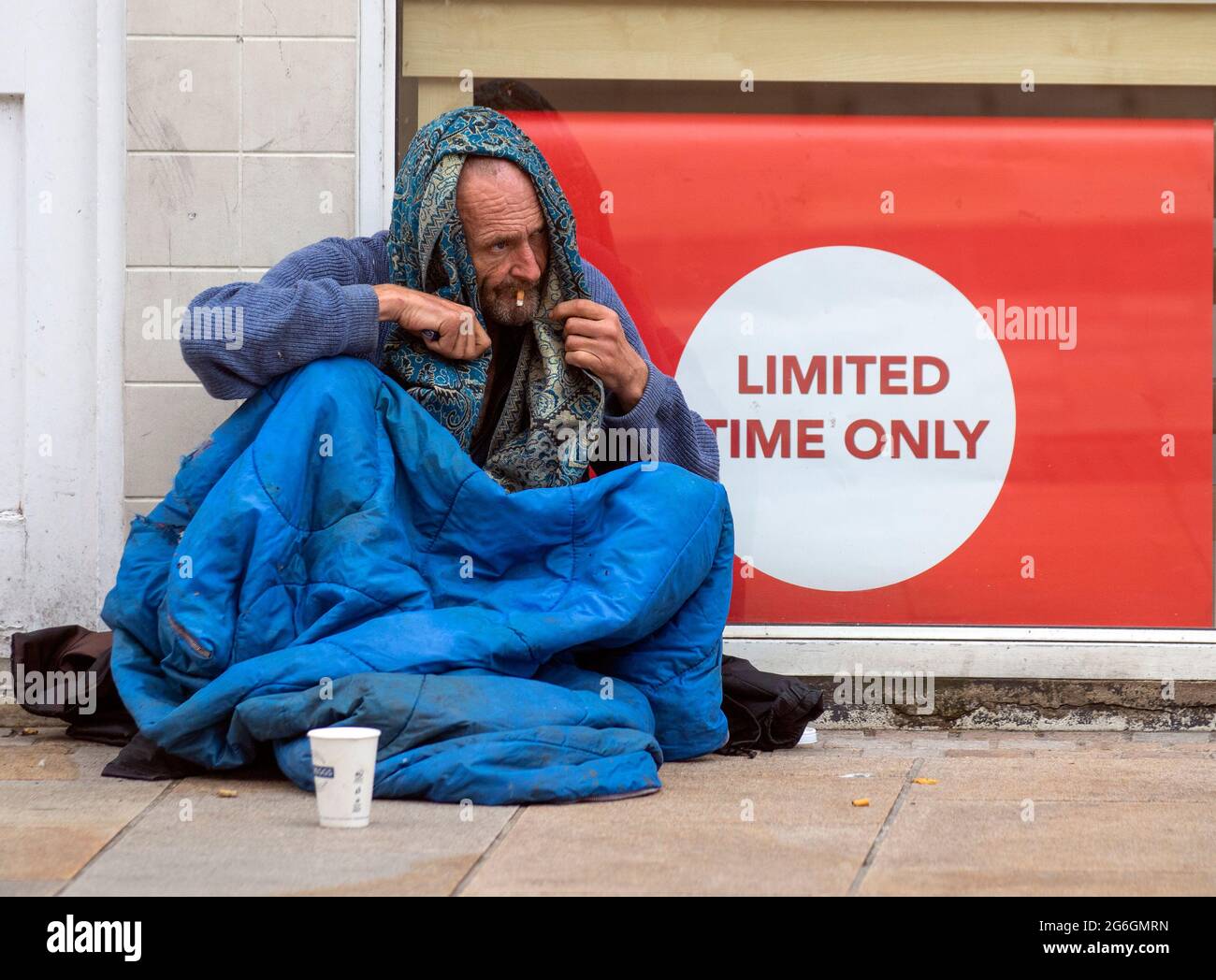 Affiche limitée dans le temps. Mendiant à Preston, Lancashire. Météo britannique juillet, 2021 homme sans-abri en mauvaise santé assis sur le trottoir à l'extérieur du magasin de cartes vendant des cartes de Noël. Les sans-abri, en particulier ceux qui dorment dur, sont gravement vulnérables pendant la pandémie. Ils sont trois fois plus susceptibles de souffrir d'un problème de santé chronique, y compris des troubles respiratoires comme la MPOC. Banque D'Images