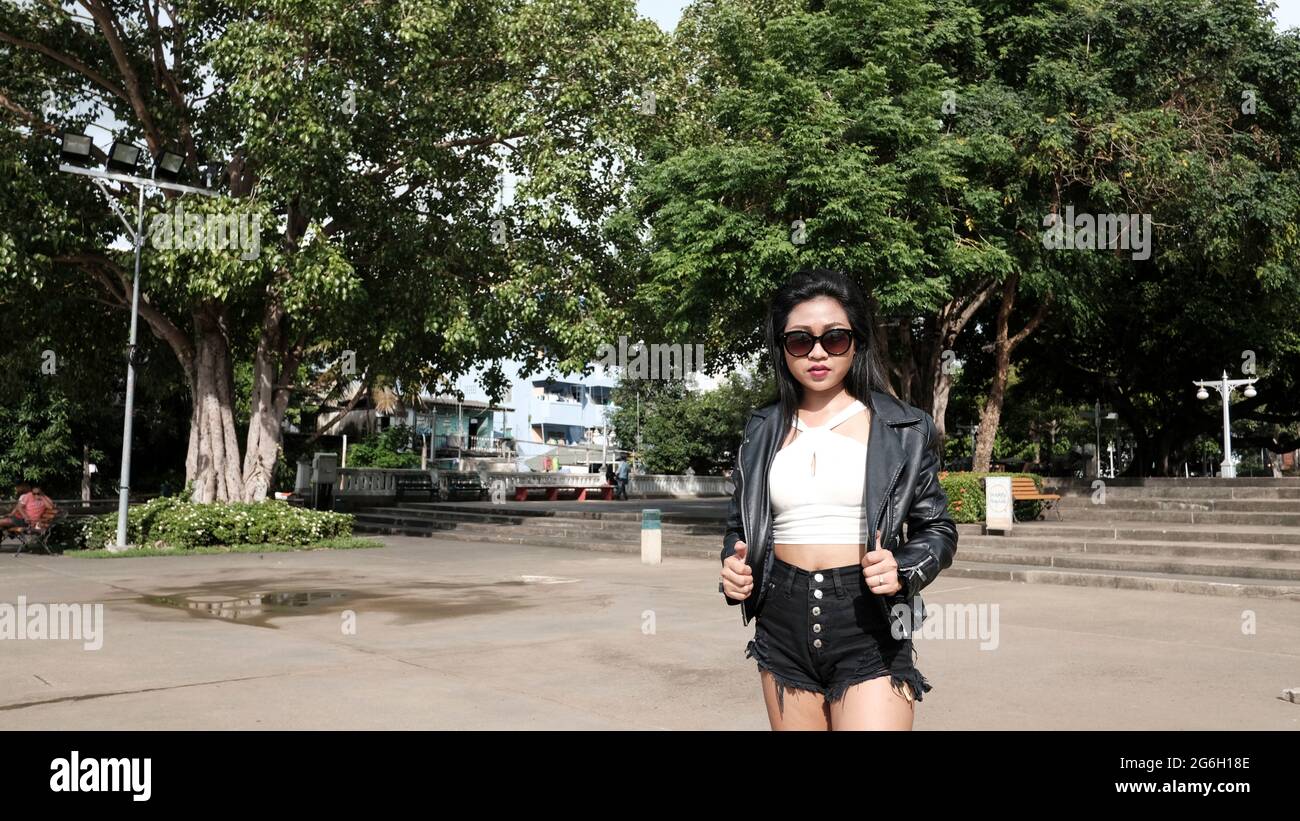 Happy Asian Girl porte des lunettes de soleil Black Leather Jacket Black Chemisier blanc comme modèle causal Walking dans le parc Bangkok Thaïlande Banque D'Images