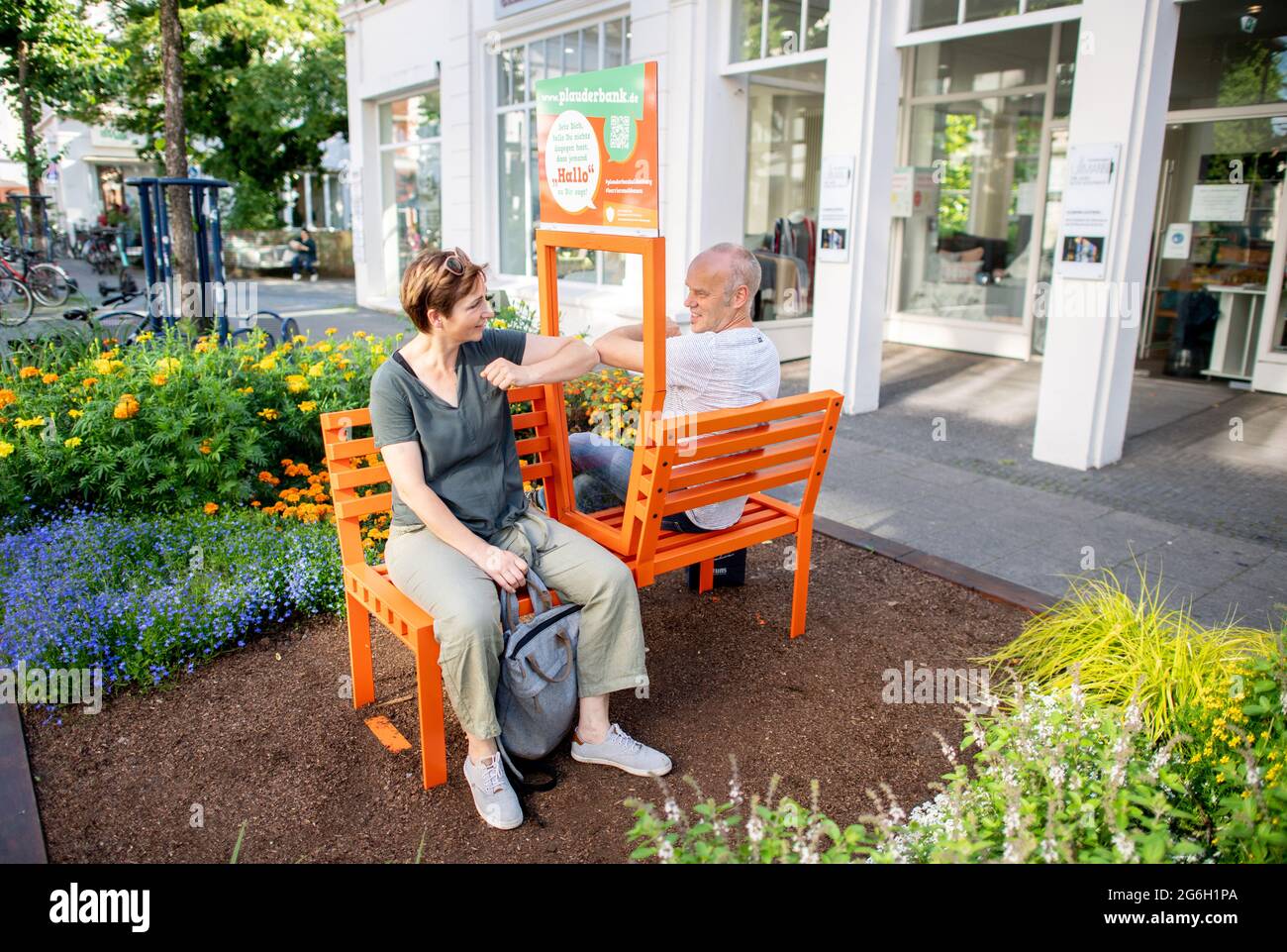 03 juillet 2021, Basse-Saxe, Oldenburg: Doris et Ansgar d'Ochtrup s'assoient sur un banc de chat dans le centre-ville d'Oldenburg. Les bancs corona-conformes sont équipés d'un panneau de verre entre les sièges et sont destinés à inviter les gens à engager la conversation avec les autres. Depuis mai, dix bancs de chat ont déjà été installés à divers endroits de la ville. Photo: Hauke-Christian Dittrich/dpa Banque D'Images