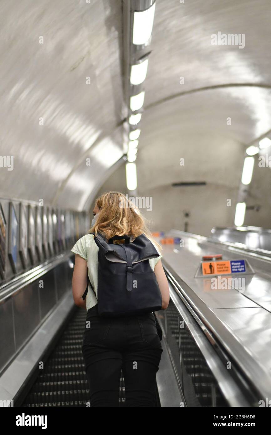 Femmes avec un sac à dos voyageant sur un escalier roulant dans le métro de londres Banque D'Images