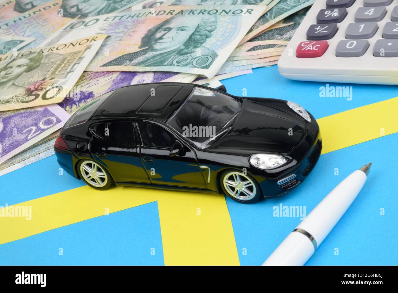 Une voiture de jouet noire sur un drapeau suédois avec des notes de Kronor,  une calculatrice et un stylo Photo Stock - Alamy