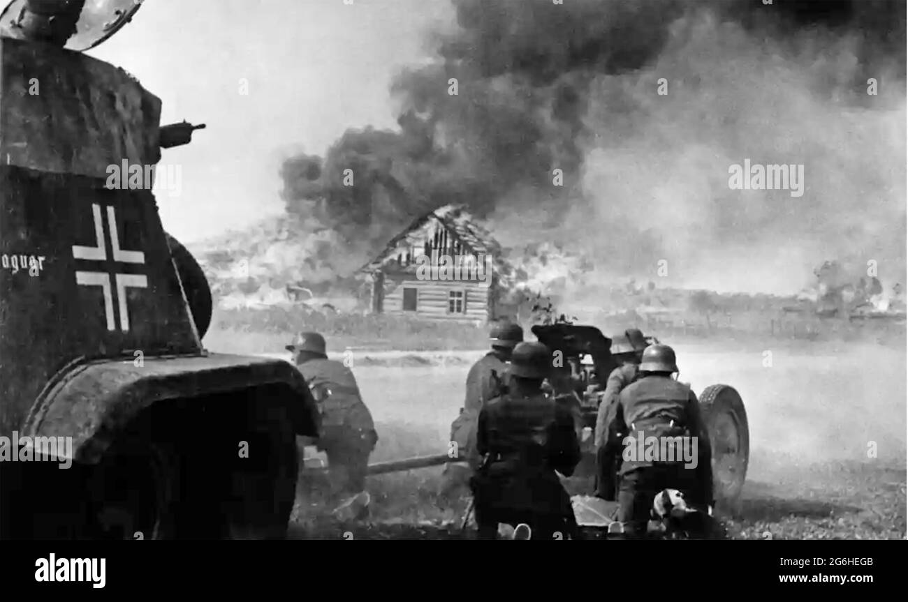 OPÉRATION BARBAROSSA juin-décembre 1941 l'invasion nazie de la Russie. Une équipe allemande d'armes anti-chars et un char léger encadrés par une maison russe flamboyante. Banque D'Images
