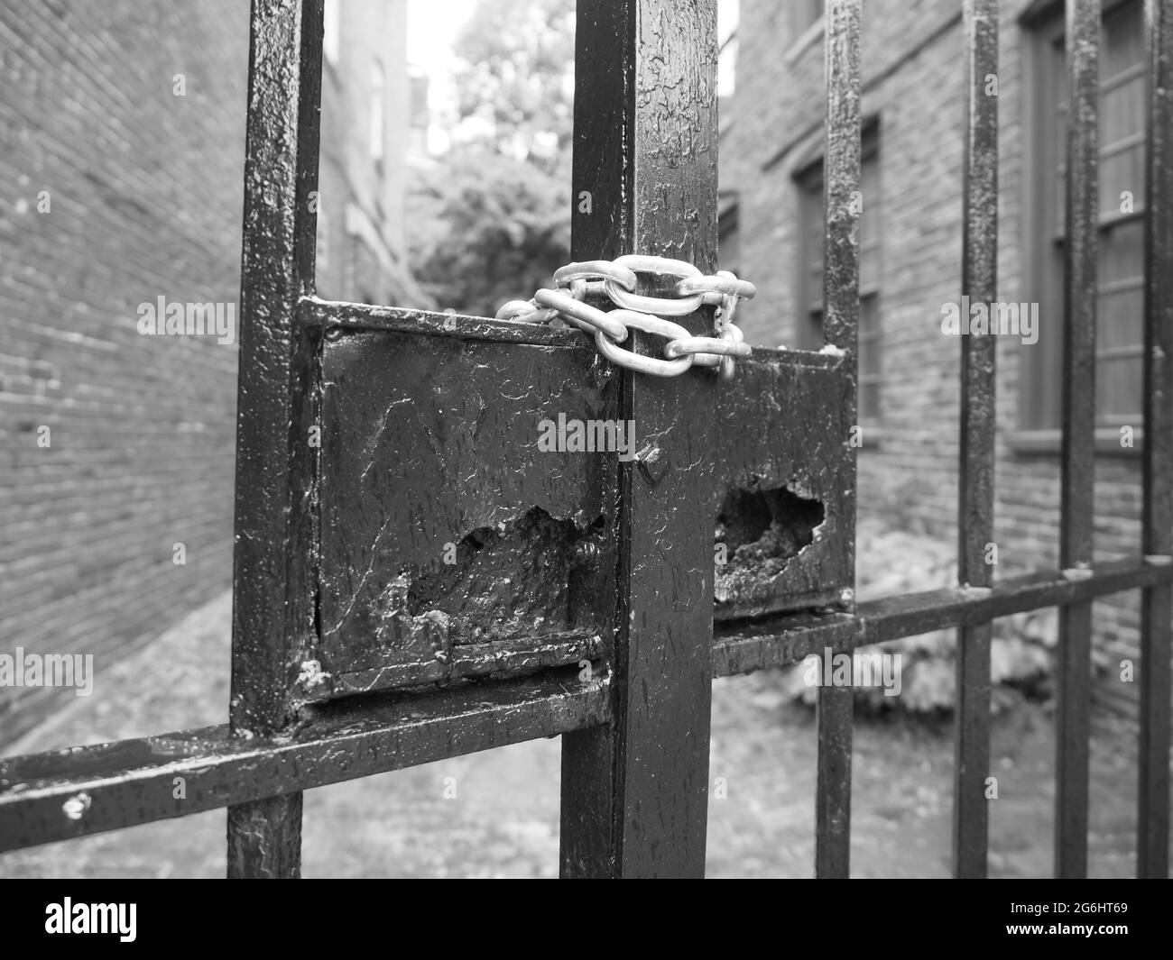 Image monochrome d'une chaîne autour d'une clôture en fer. Banque D'Images