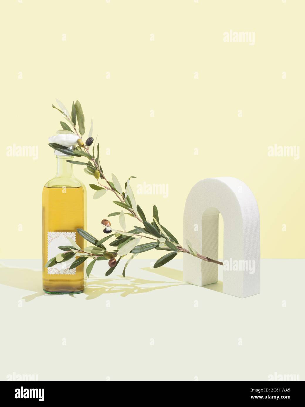 Branche d'olivier vert sur fond jaune pastel et turquoise. Un objet 3d blanc. Concept de produit d'huile d'olive. Ombres de lumière naturelle et dures. Minimale Banque D'Images