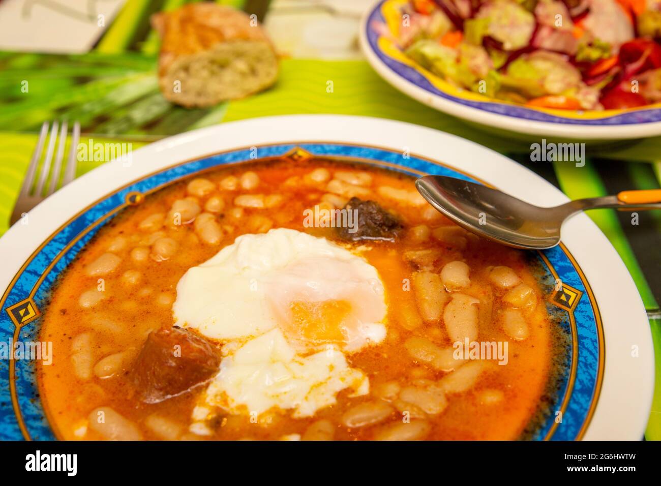 Vue sur les assiettes avec la typique Fabada asturiana espagnole et salade mixte Banque D'Images
