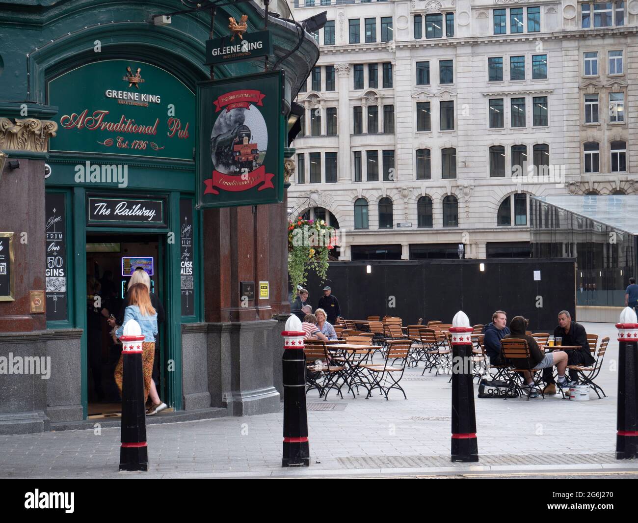 Greene King Railway Tavern, Londres, avec des clients assis à l'extérieur, et les Bollards de la ville de Londres en premier plan Banque D'Images