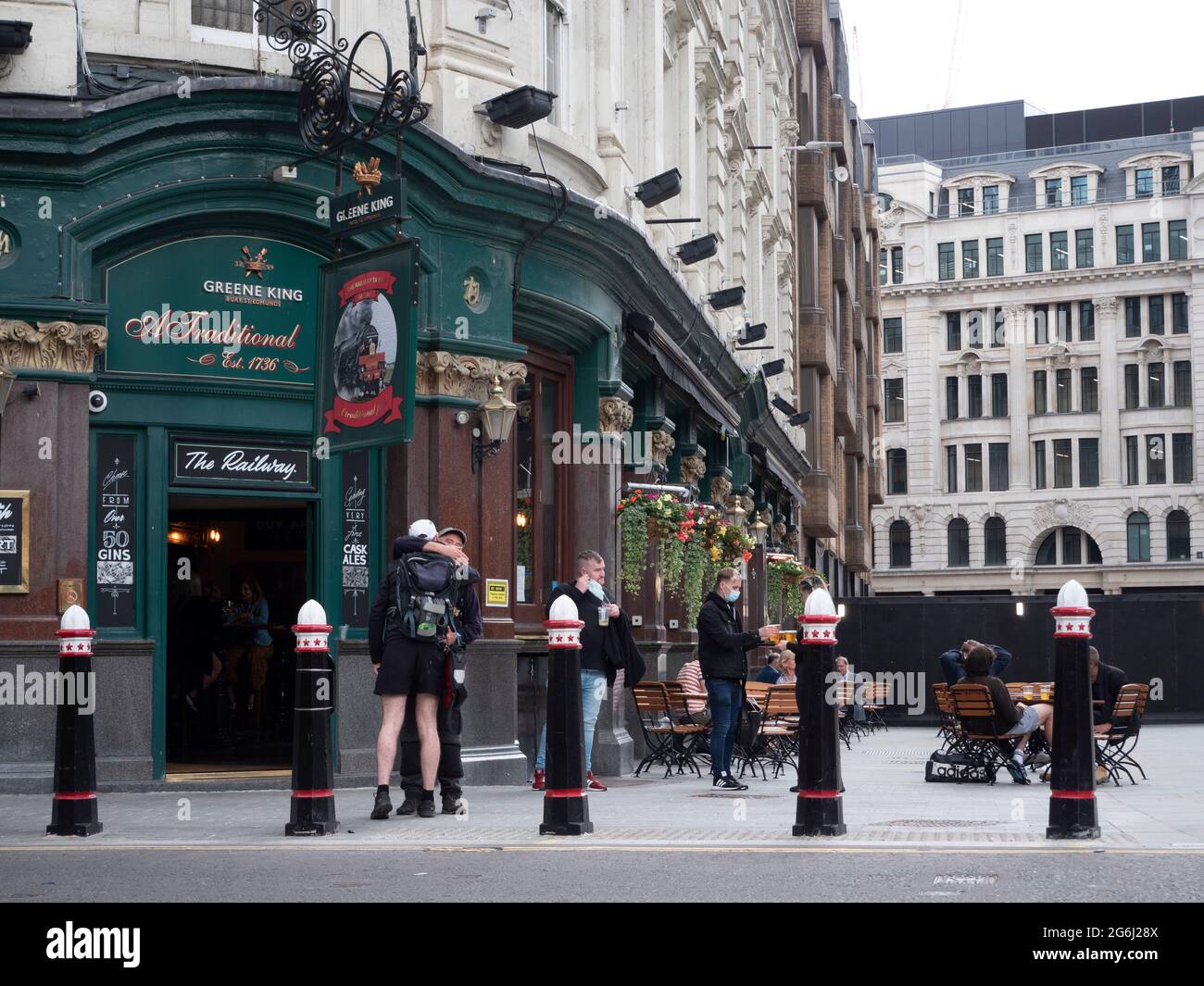 Greene King Railway Tavern, Londres, avec des clients assis à l'extérieur, et les Bollards de la ville de Londres en premier plan Banque D'Images